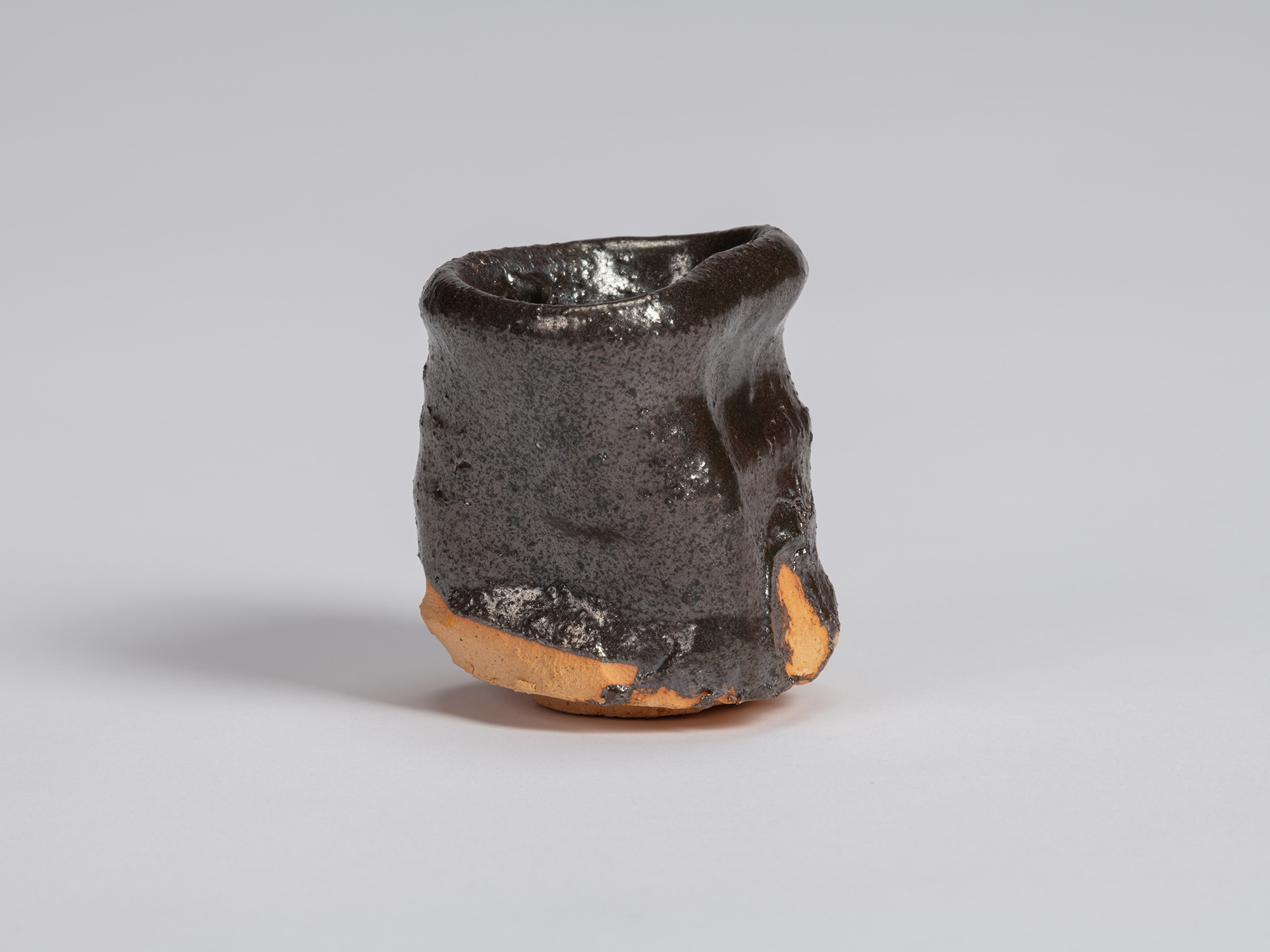 View of a Kuro Guinomi by Shiro Tsujimura, with a tall, slightly waisted cylindrical form, irregular...