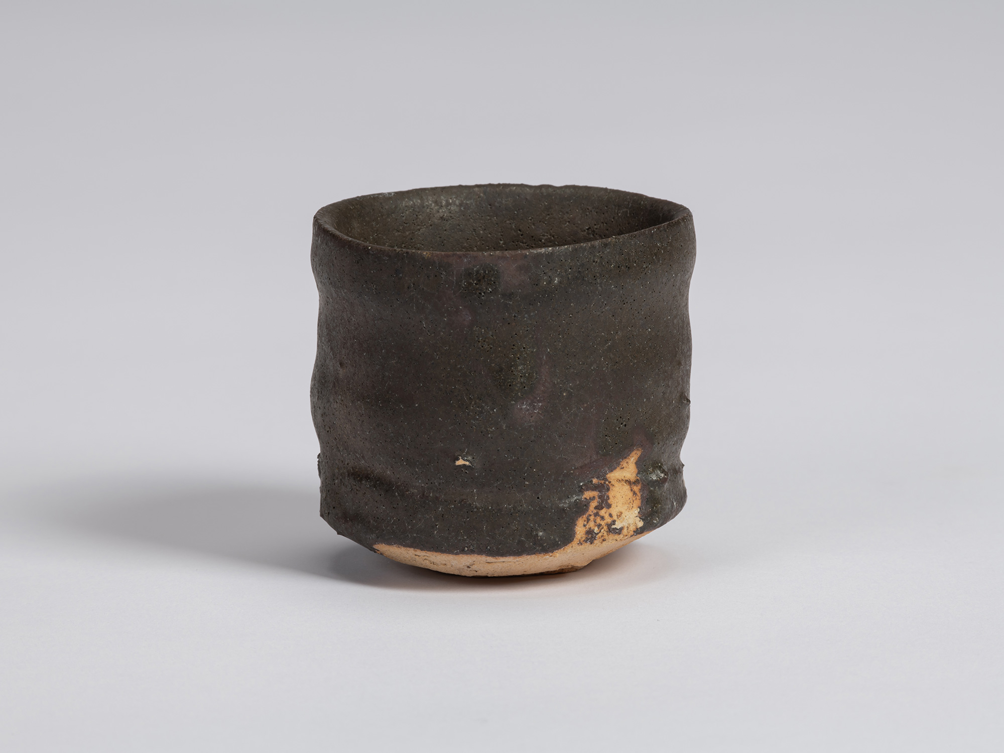 View of a Kuro Guinomi by Shiro Tsujimura, with a tall cylindrical form, subtly irregular rim,...
