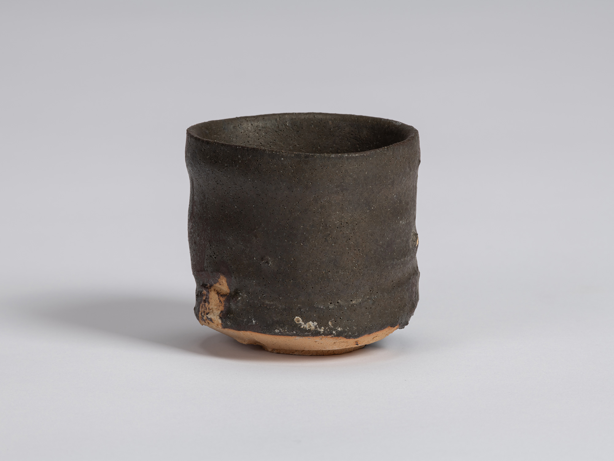 View of a Kuro Guinomi by Shiro Tsujimura, with a tall cylindrical form, subtly irregular rim,...