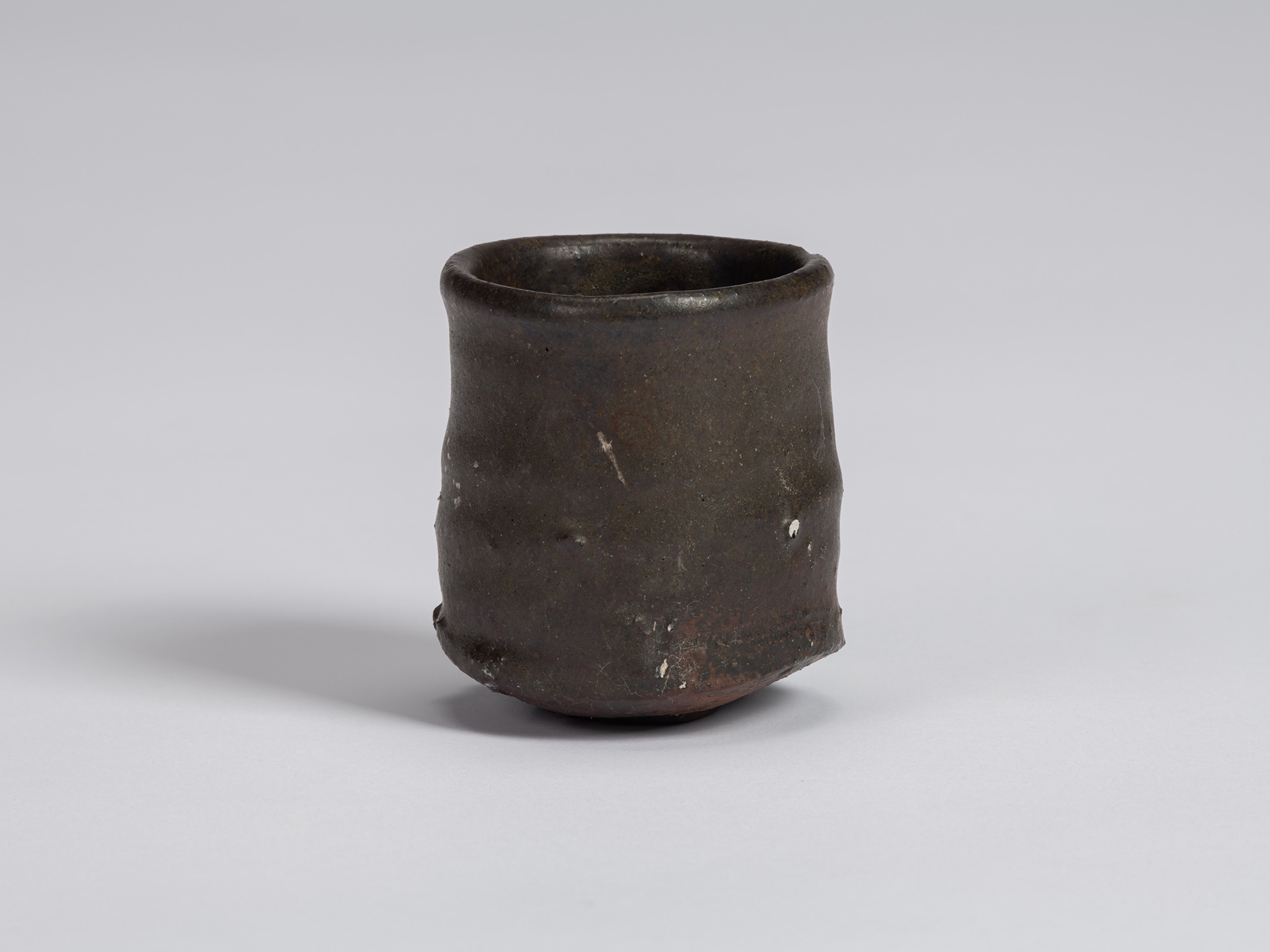 View of a Kuro Guinomi by Shiro Tsujimura, with a tall, slightly waisted cylindrical form, rounded...