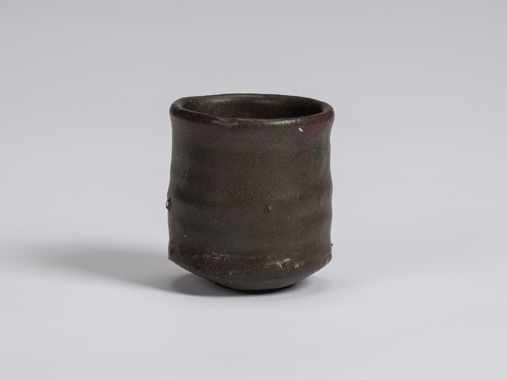View of a Kuro Guinomi by Shiro Tsujimura, with a tall, slightly waisted cylindrical form, rounded...