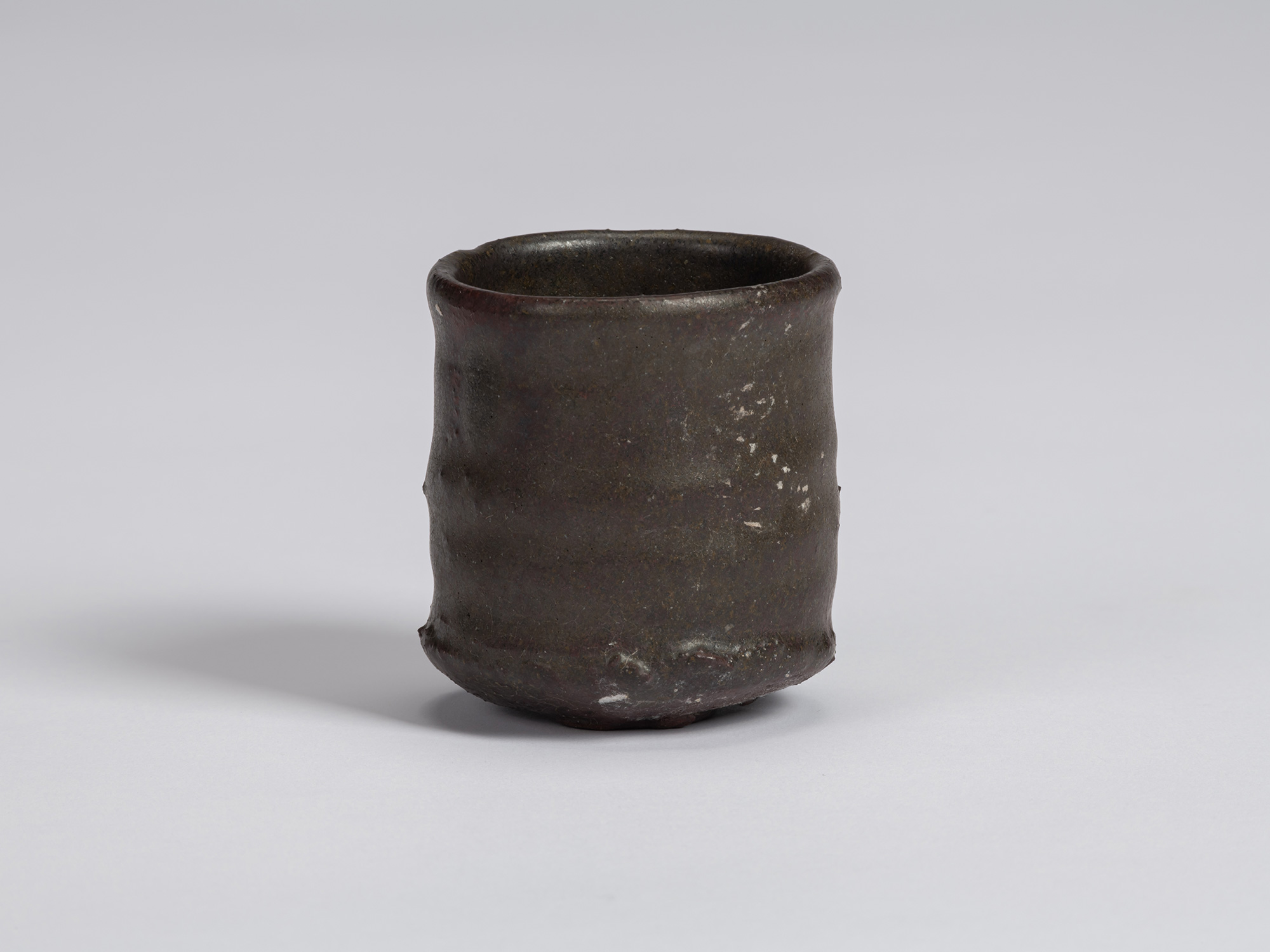 View of a Kuro Guinomi by Shiro Tsujimura, with a tall, slightly waisted cylindrical form, rounded...