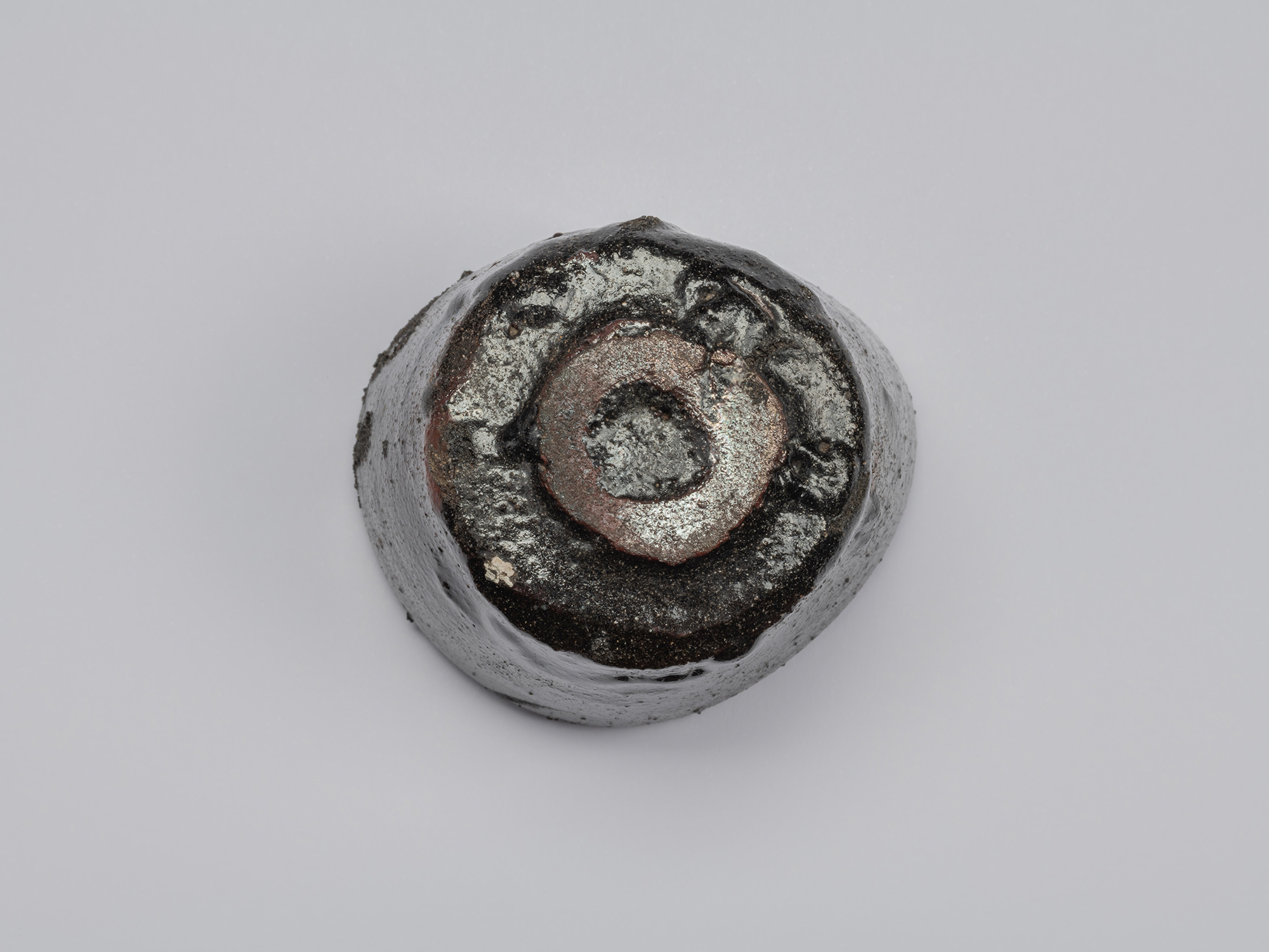 Bottom view of the Kuro Guinomi, showing the roughly formed circular foot with exposed reddish-brown...