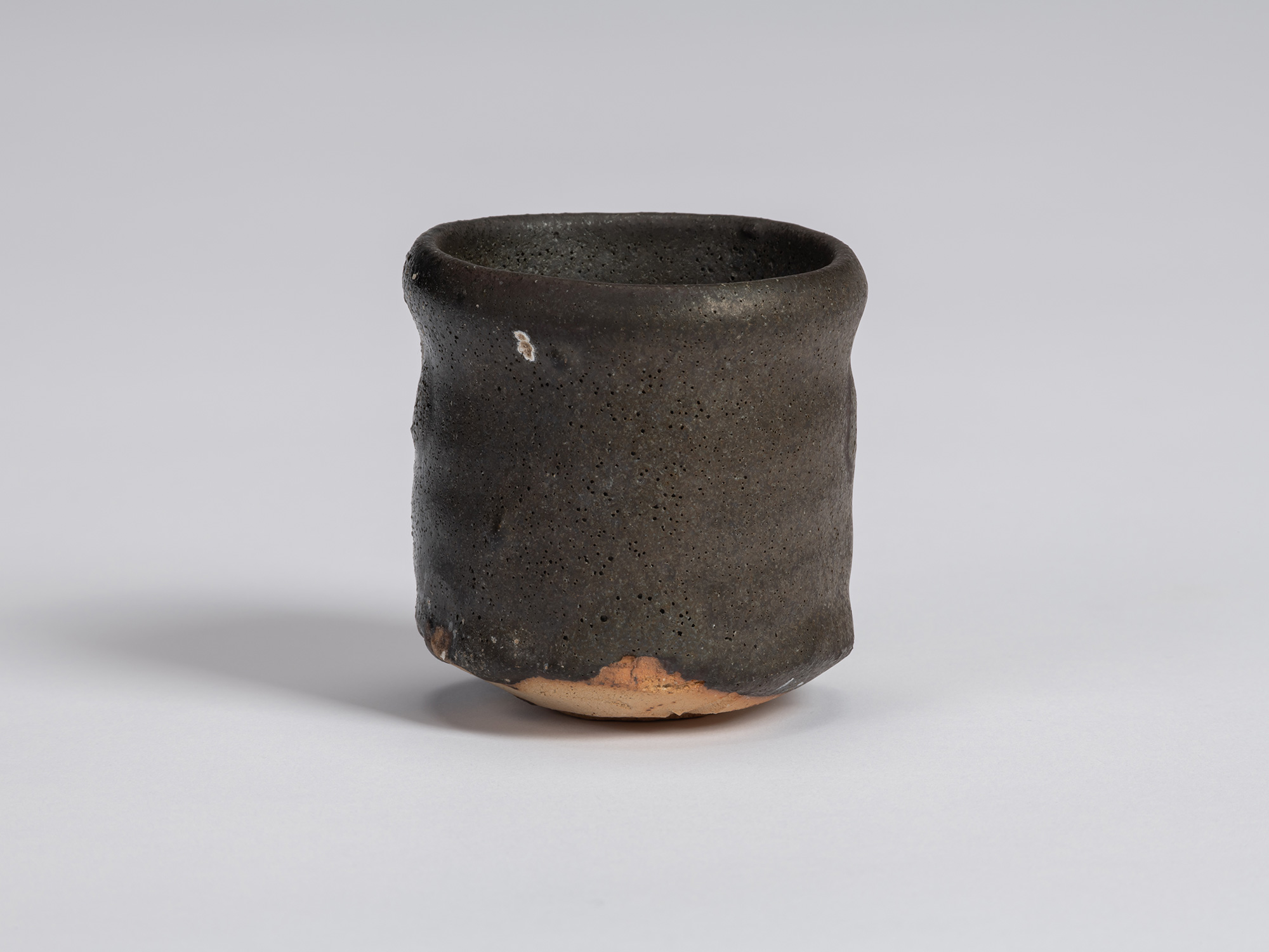 Kuro guinomi by Shiro Tsujimura with a tall, slightly irregular cylindrical form, rounded rim,...