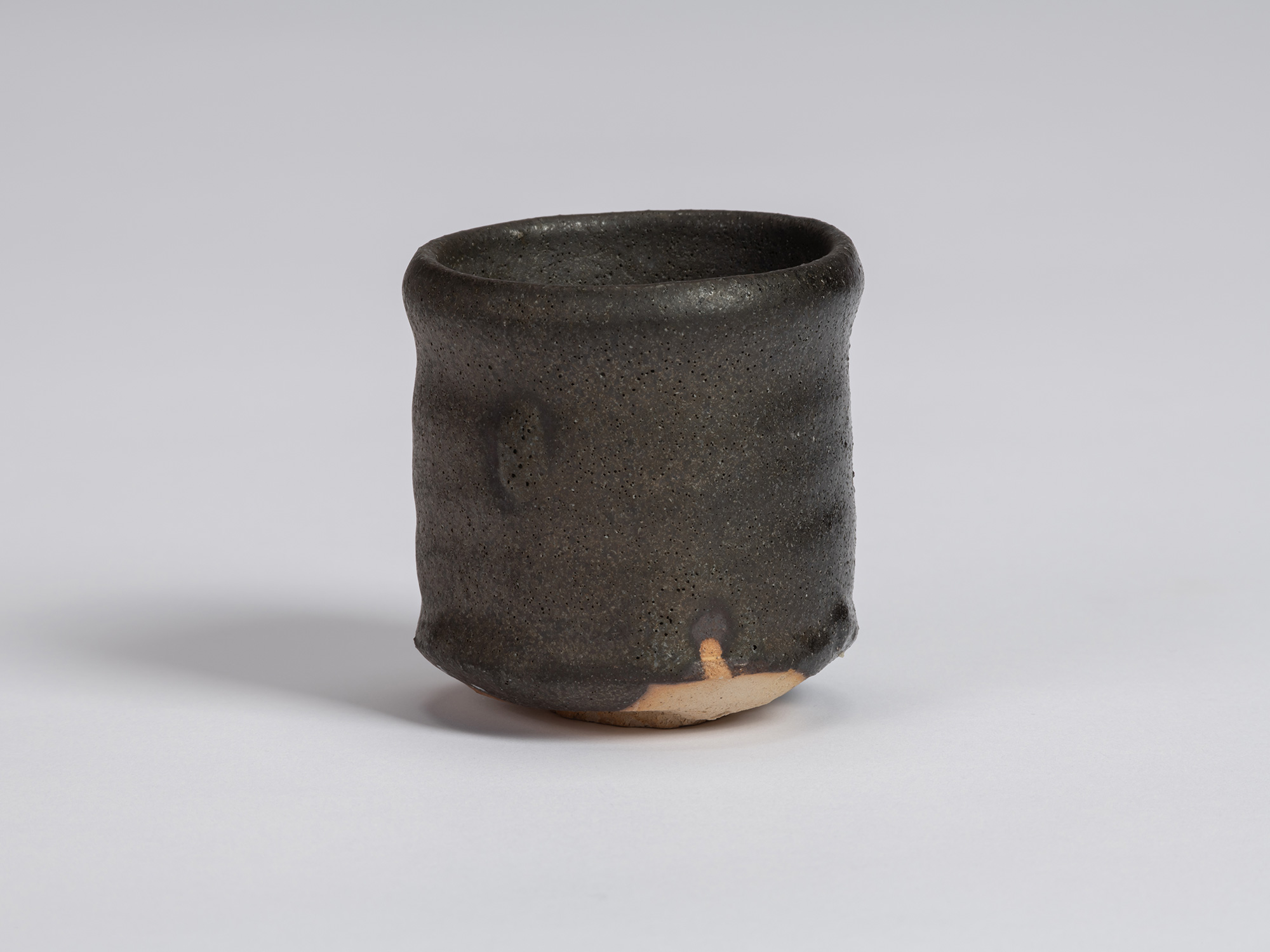 Kuro guinomi by Shiro Tsujimura with a tall, slightly irregular cylindrical form, rounded rim,...