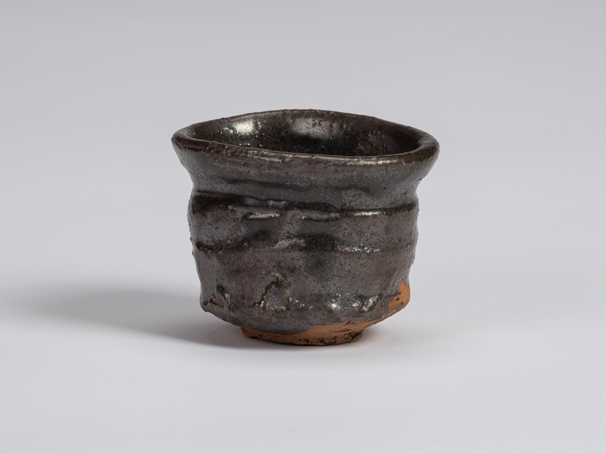 Kuro guinomi by Shiro Tsujimura with an irregular cylindrical form, flared rim, horizontal ridges,...
