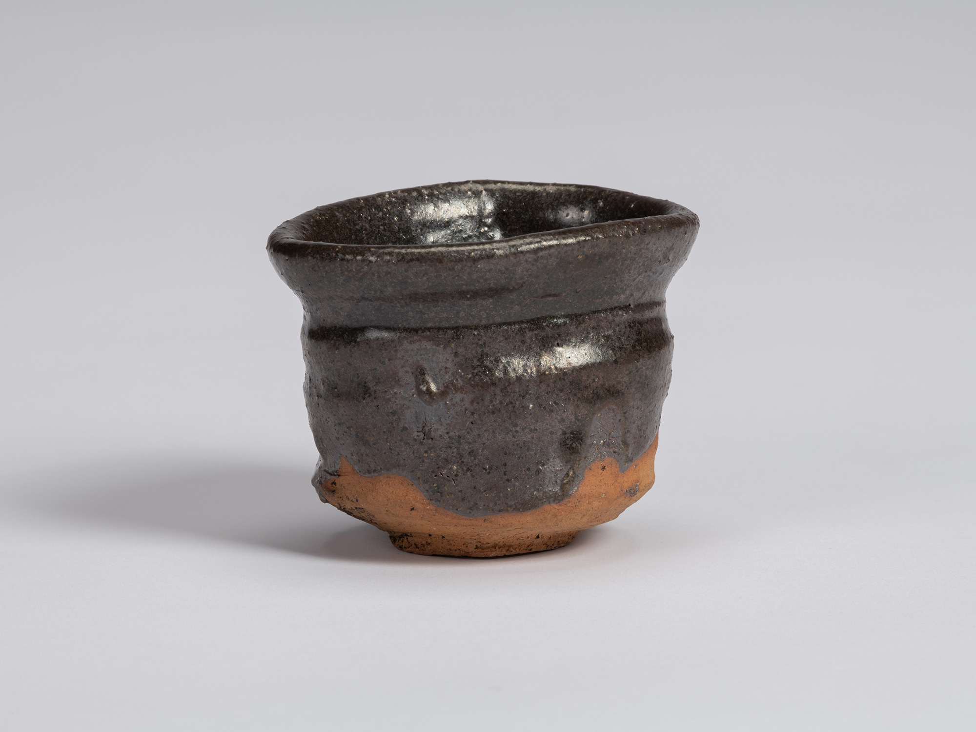 Kuro guinomi by Shiro Tsujimura with an irregular cylindrical form, flared rim, horizontal ridges,...