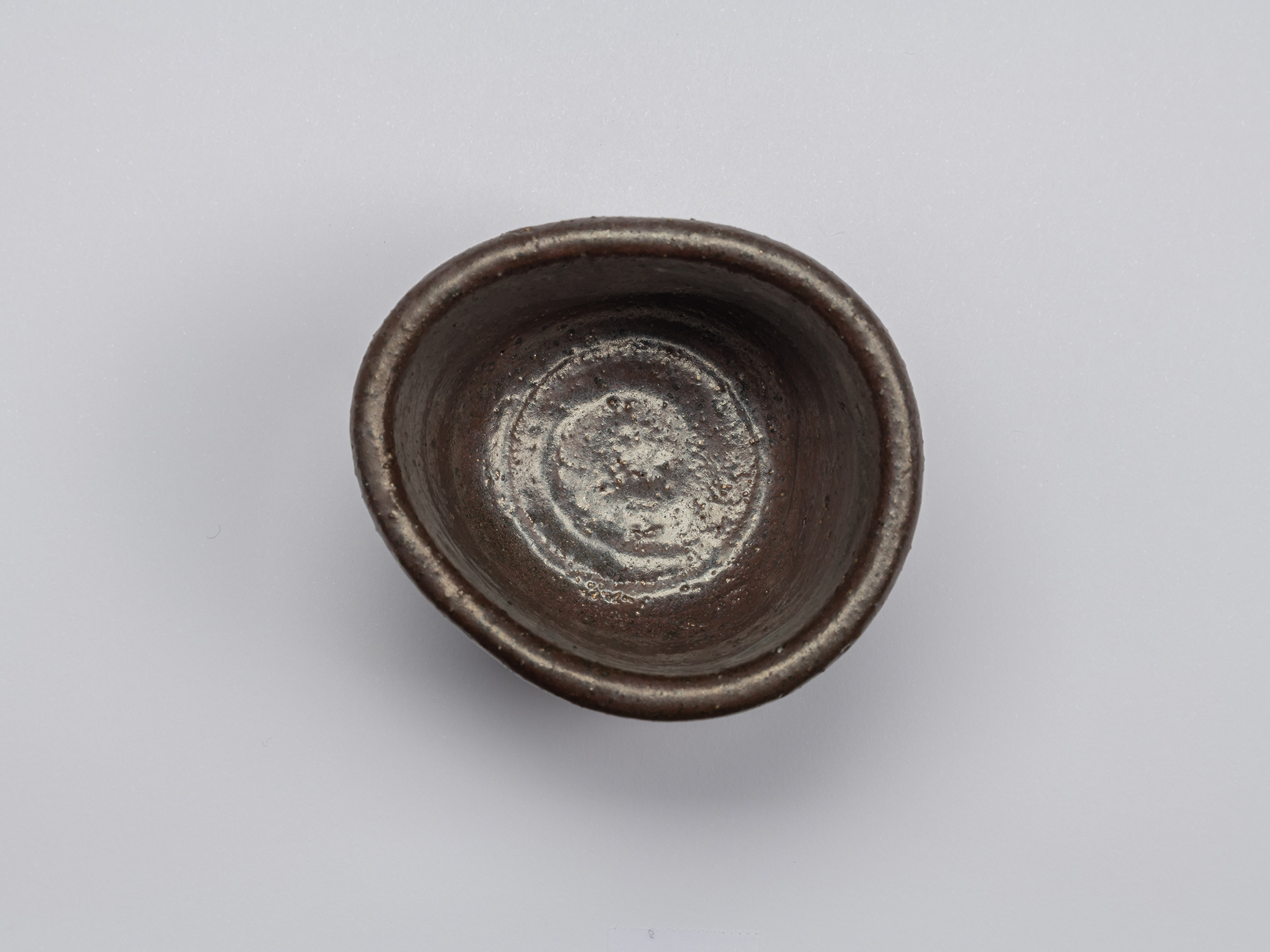 Top view of Kuro Guinomi by Shiro Tsujimura, showing an irregular rounded rim and dark glazed interior...