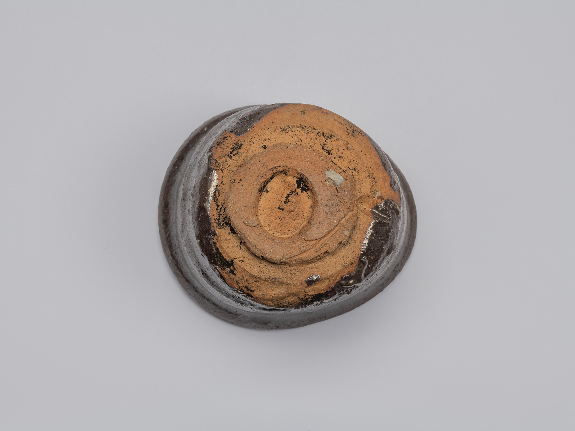 Underside of Kuro Guinomi by Shiro Tsujimura, showing a roughly formed circular foot and broad...