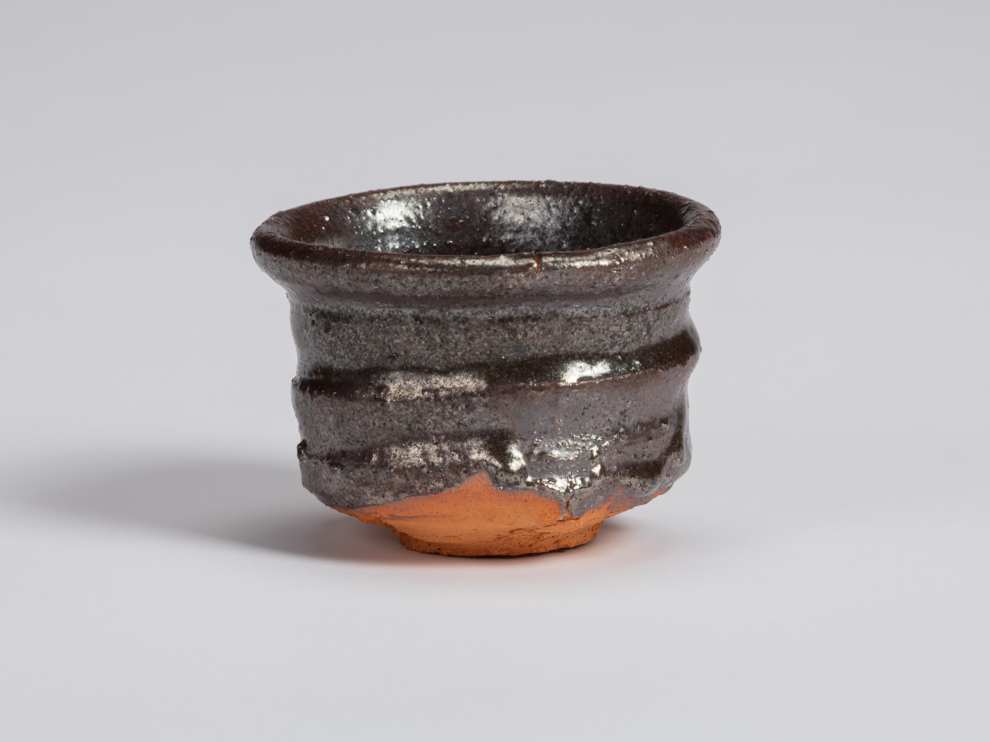 Kuro Guinomi by Shiro Tsujimura, with a broad cylindrical form, glossy black-brown glaze, horizontal...
