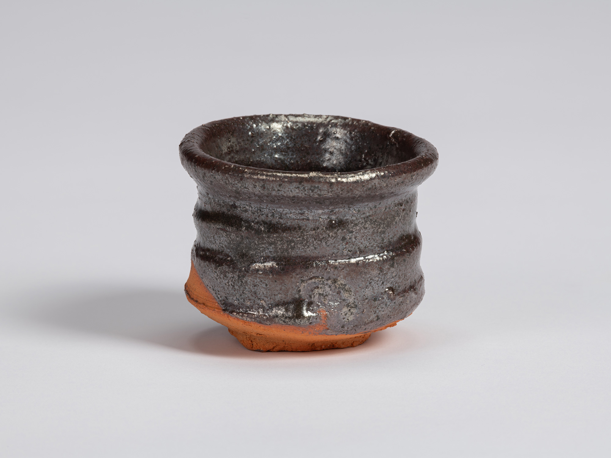 Kuro Guinomi by Shiro Tsujimura, with a broad cylindrical form, glossy black-brown glaze, horizontal...