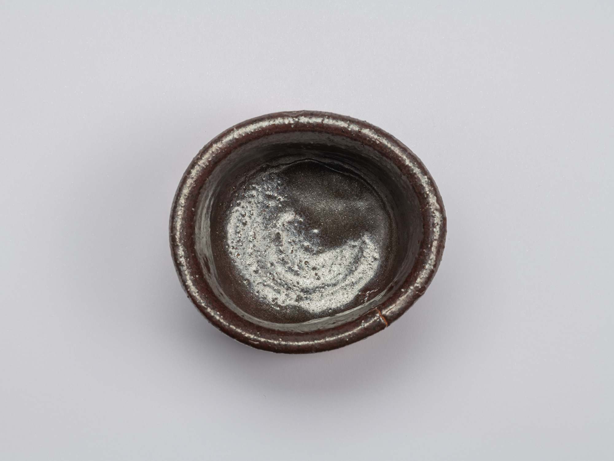 Top view of Kuro Guinomi by Shiro Tsujimura, showing a thick, irregular rim and dark glazed interior...