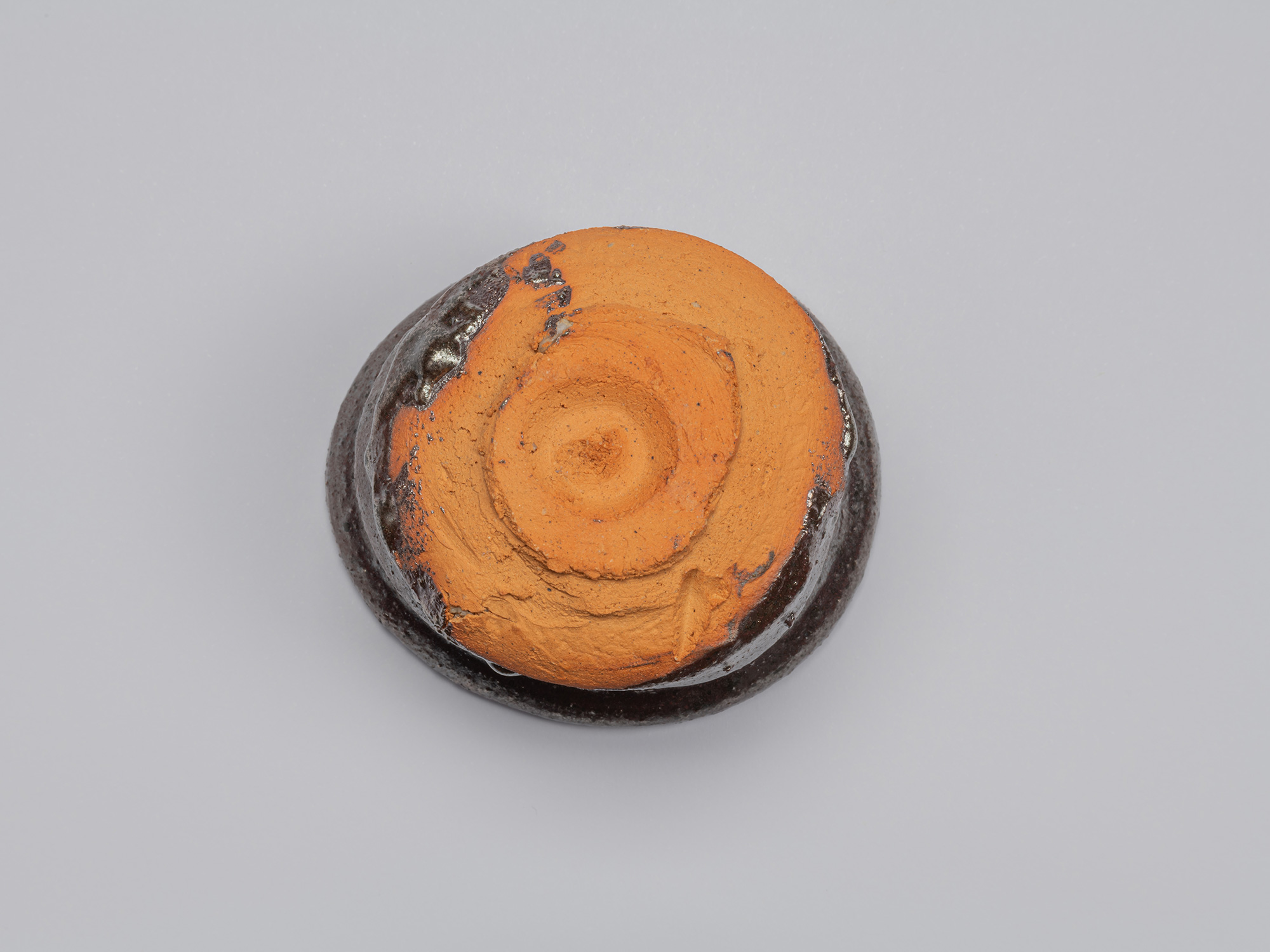 Underside of Kuro Guinomi by Shiro Tsujimura, showing a roughly formed circular foot and broad...