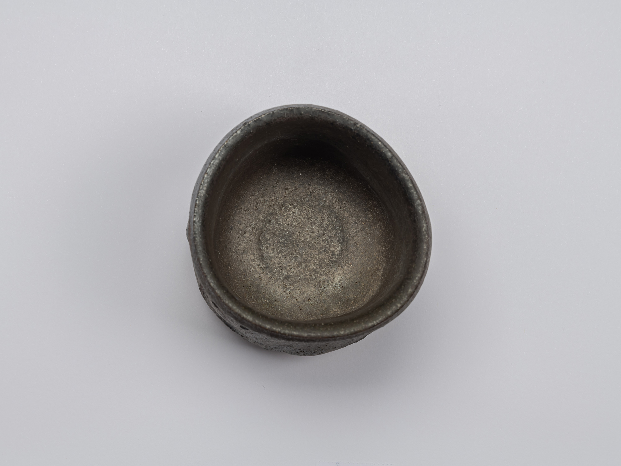 Aerial view of Kuro Guinomi by Shiro Tsujimura, showing an irregular rounded rim and dark, matte...