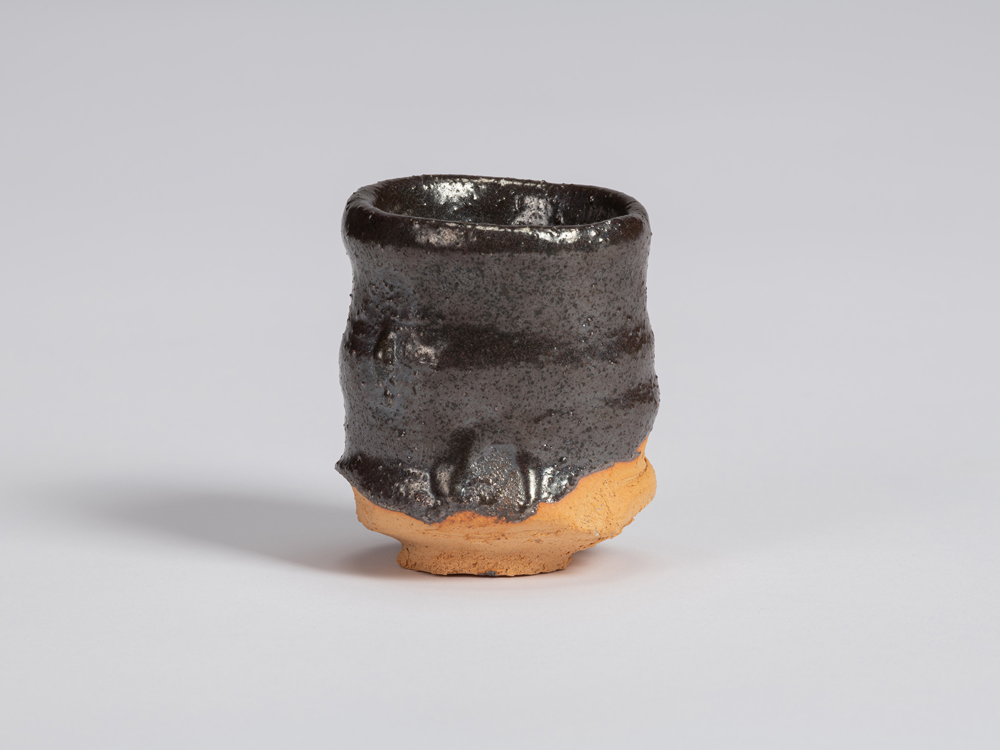 Kuro Guinomi by Shiro Tsujimura, with a slender cylindrical form, glossy black glaze, horizontal...