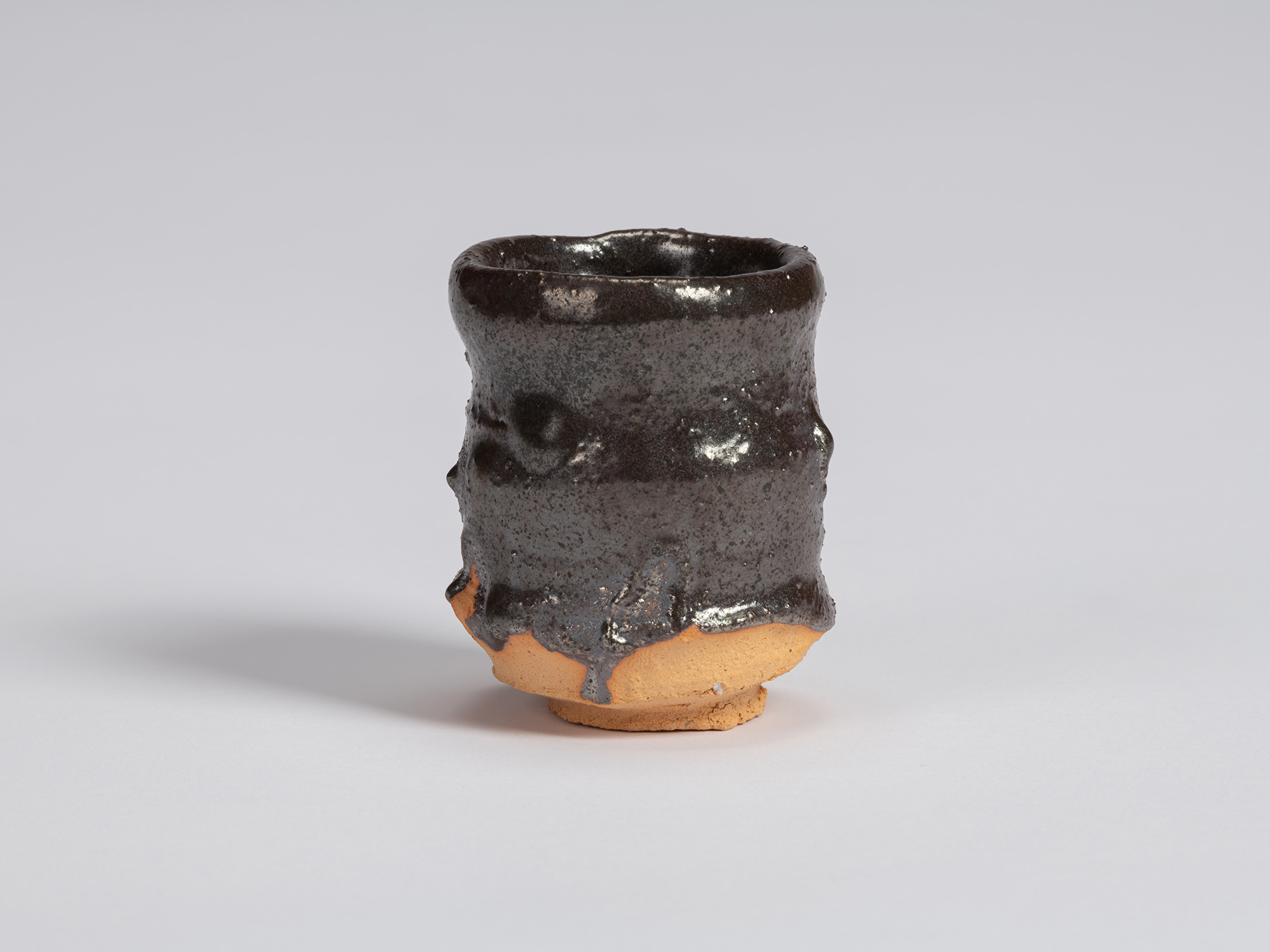 Kuro Guinomi by Shiro Tsujimura, with a slender cylindrical form, glossy black glaze, horizontal...