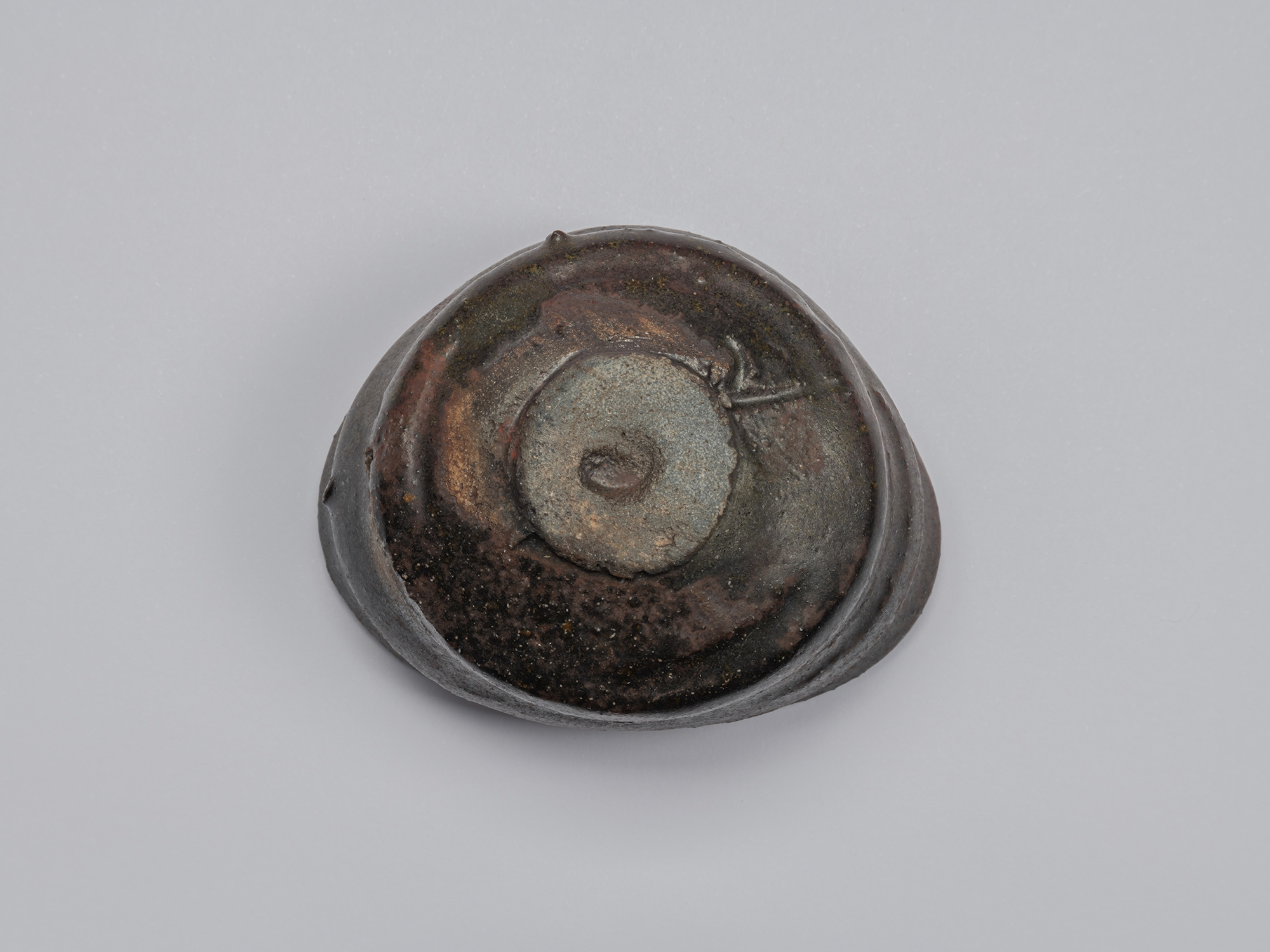 Underside of Kuro Guinomi by Shiro Tsujimura, showing a small circular foot surrounded by dark...