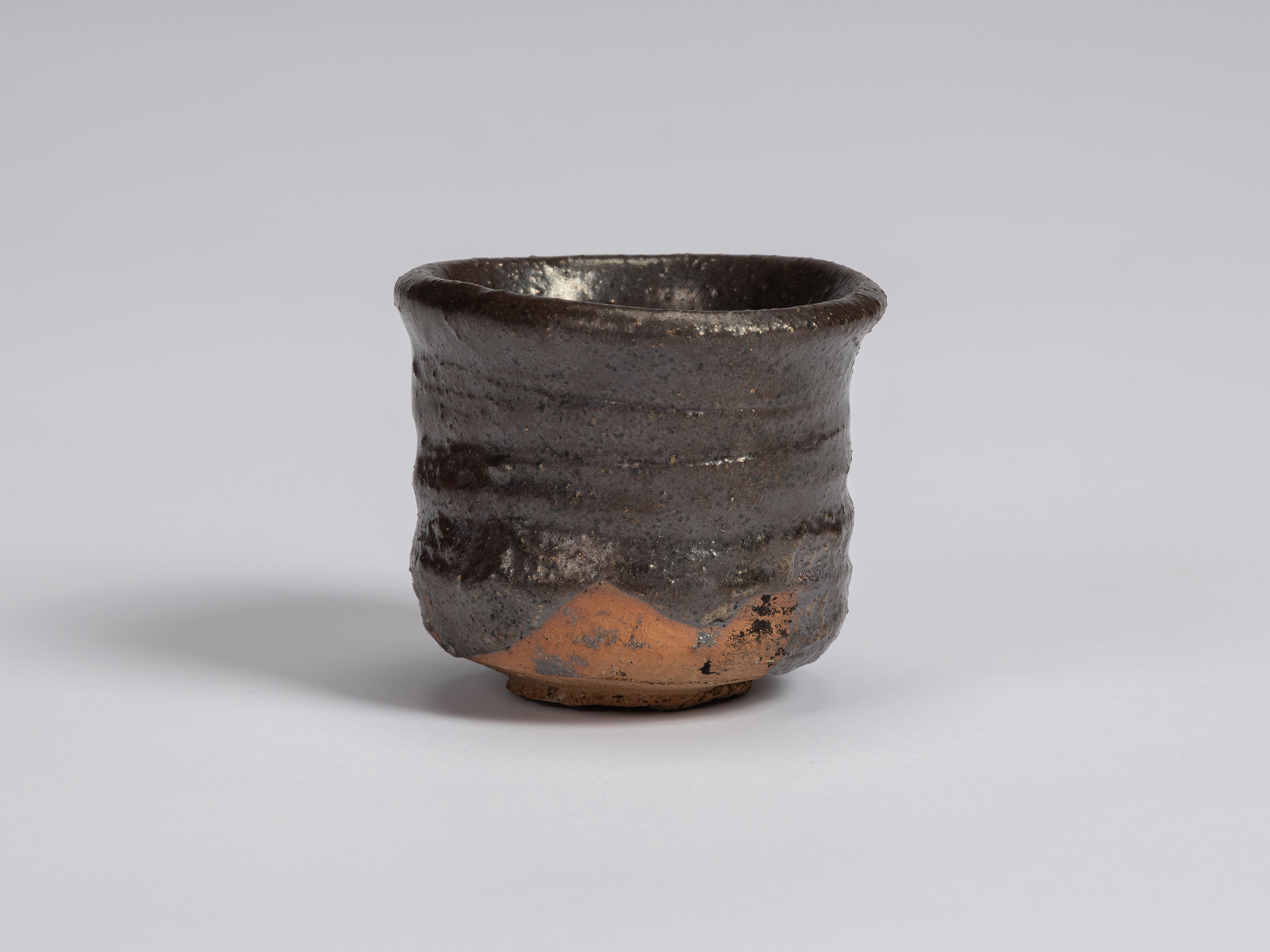 View of a Kuro Guinomi by Shiro Tsujimura, with a cylindrical form, slightly flared irregular rim,...