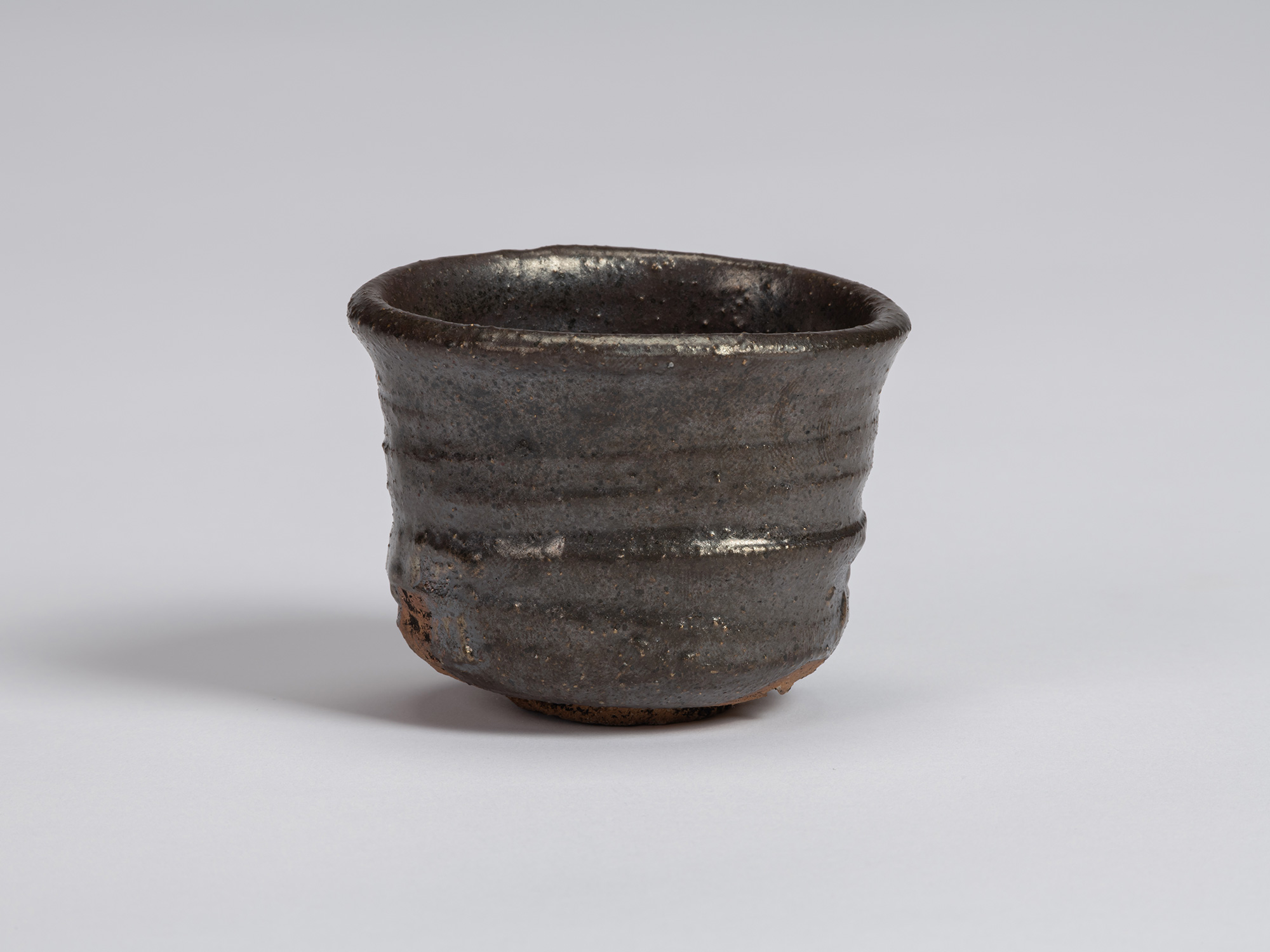 View of a Kuro Guinomi by Shiro Tsujimura, with a cylindrical form, slightly flared irregular rim,...