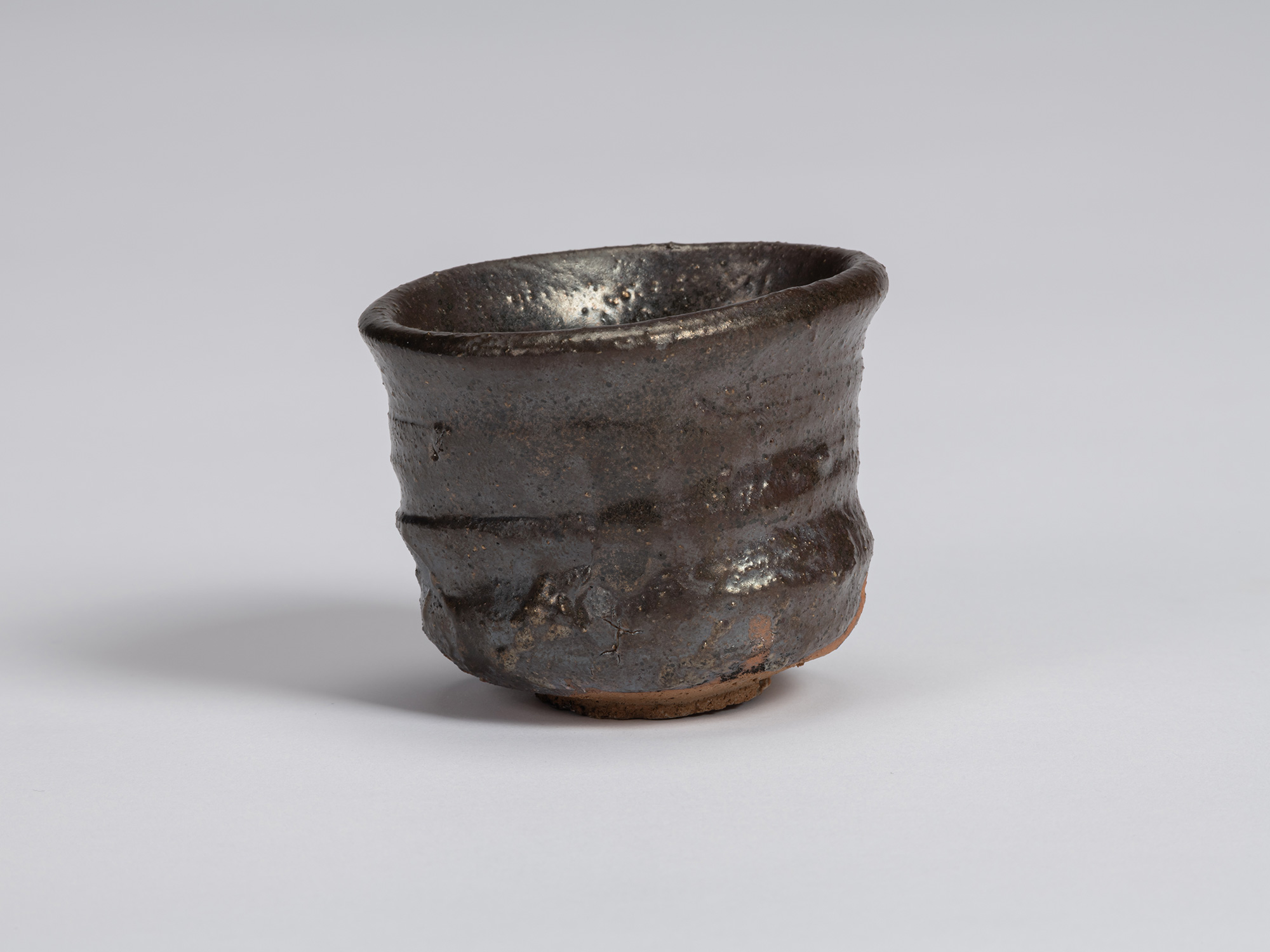 View of a Kuro Guinomi by Shiro Tsujimura, with a cylindrical form, slightly flared irregular rim,...