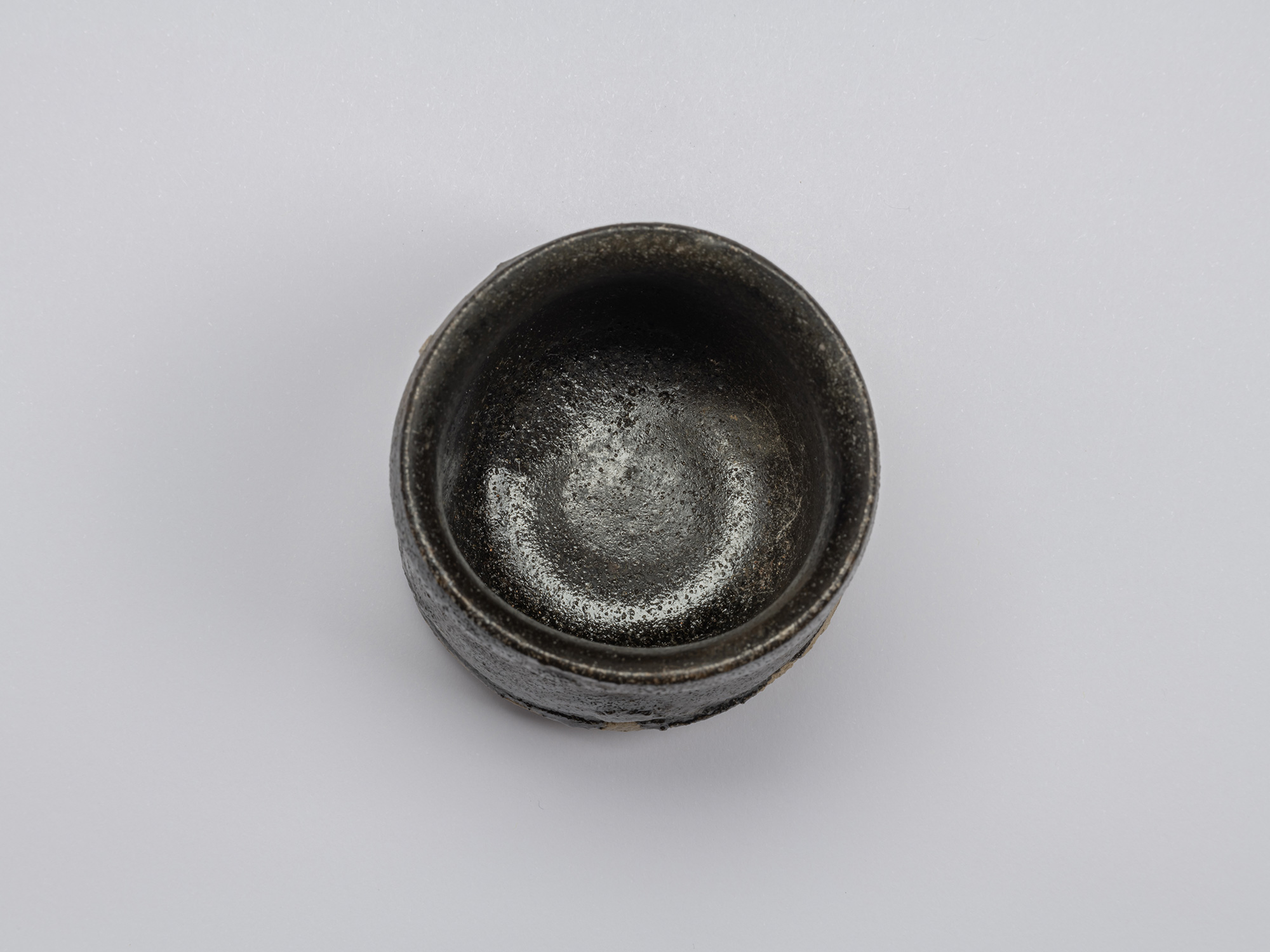 Interior view of Kuro Guinomi by Shiro Tsujimura, showing a dark, glossy black-glazed surface with...