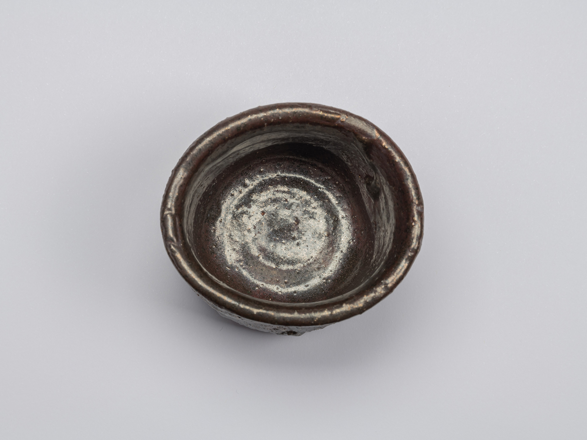 Interior view of Kuro Guinomi by Shiro Tsujimura, showing a glossy dark brown-black glaze, irregular...