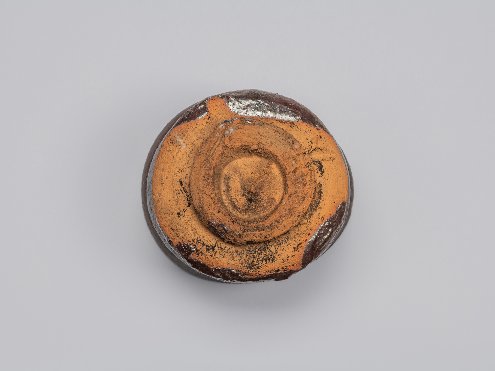 Underside view of Kuro Guinomi by Shiro Tsujimura, showing a roughly formed circular foot and exposed...