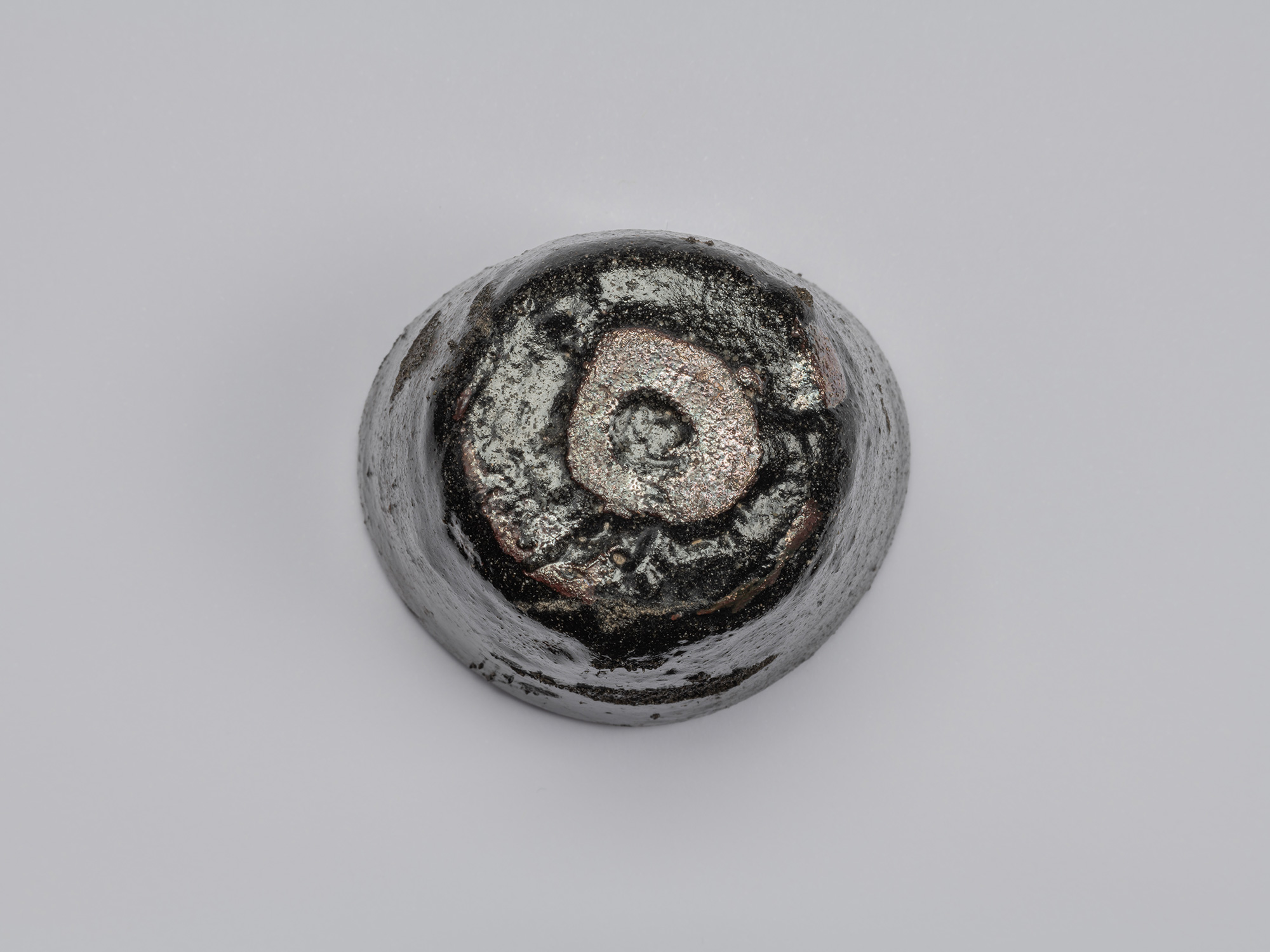 Kuro Guinomi by Shiro Tsujimura, underside view, showing the small irregular foot covered in metallic...