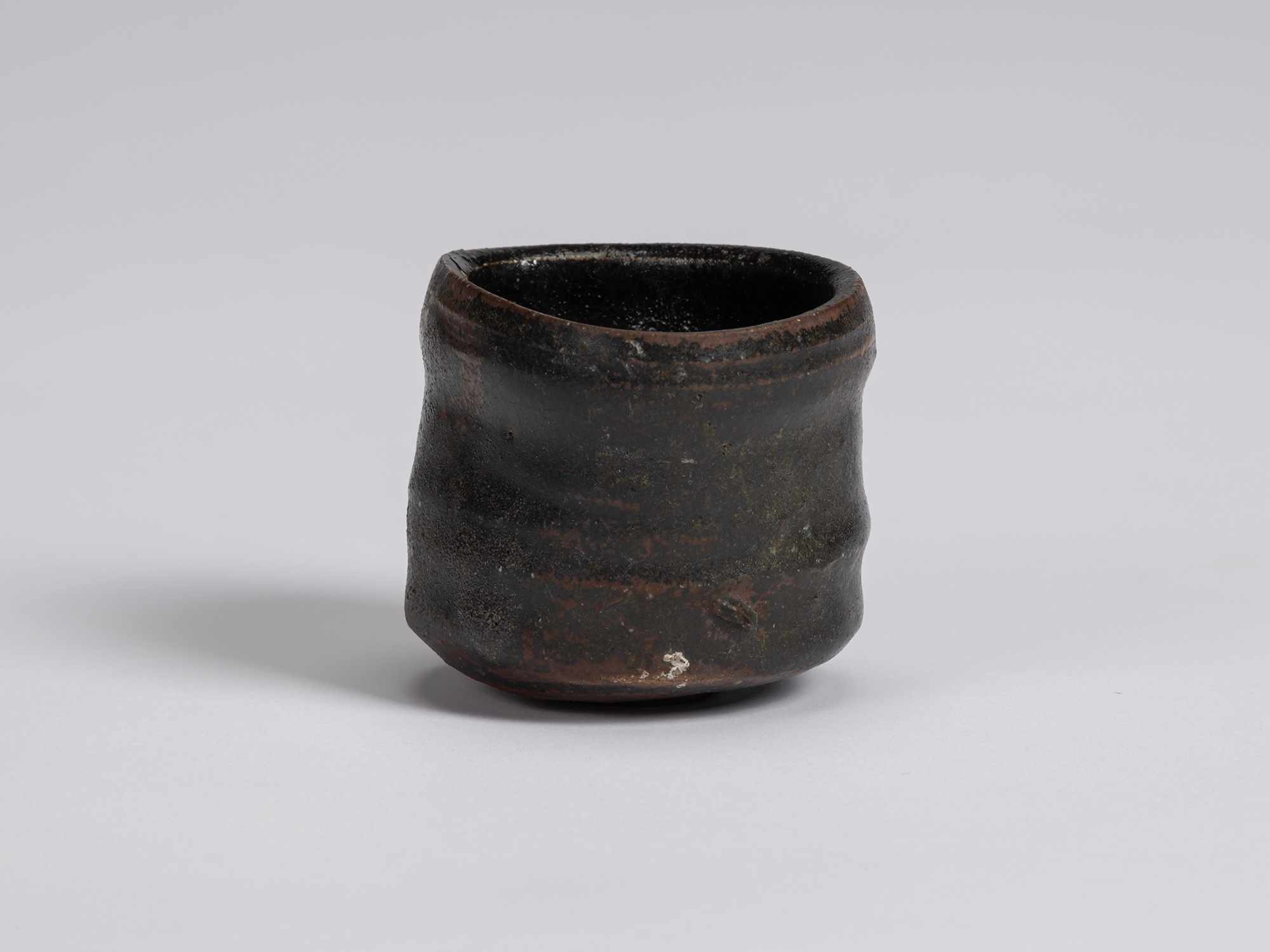 Kuro Guinomi by Shiro Tsujimura, front view, with a cylindrical form, irregular rim, horizontal...