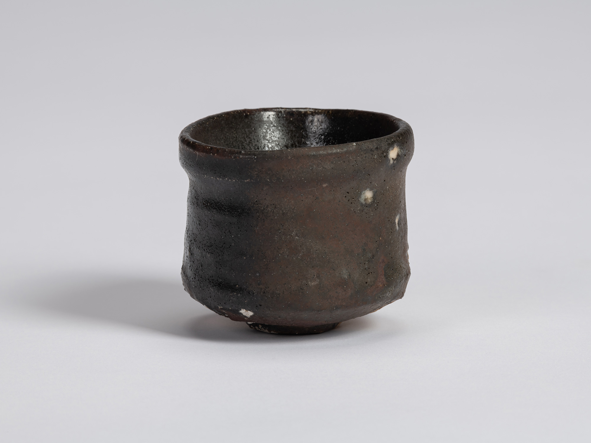 Kuro Guinomi by Shiro Tsujimura, alternate view, showing a dark black-brown glazed surface with...