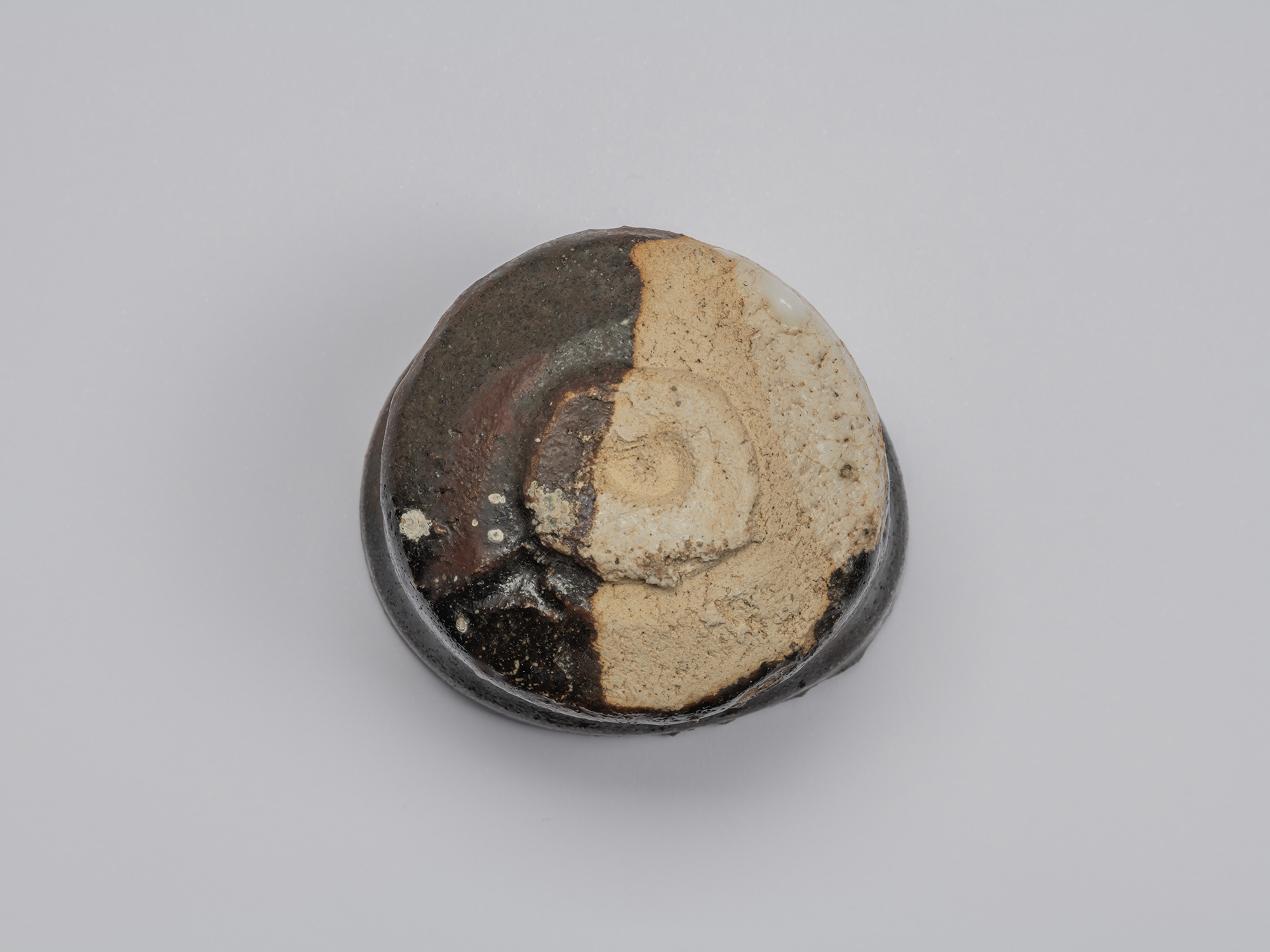 Kuro Guinomi by Shiro Tsujimura, underside view, showing an irregular foot surrounded by exposed...