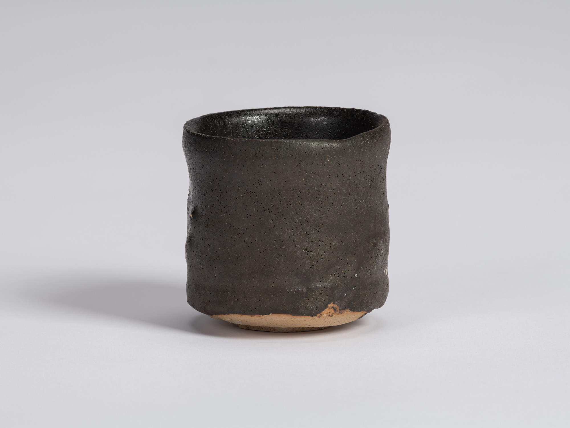 Kuro Guinomi by Shiro Tsujimura, front view, with a tall cylindrical form, subtly irregular rim,...
