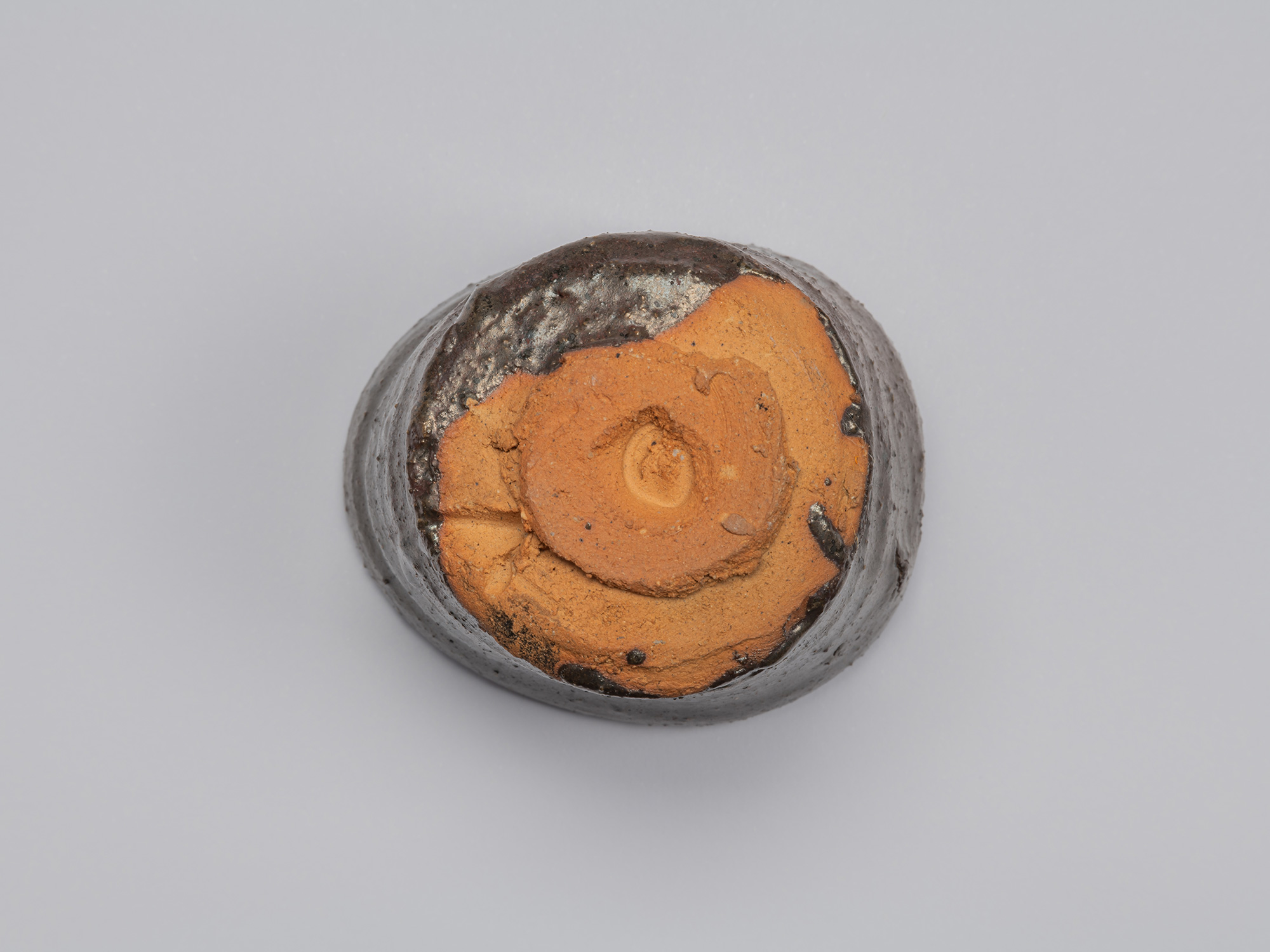 Underside of Shiro Tsujimura’s Kuro Guinomi, showing a roughly formed circular foot and broad area...