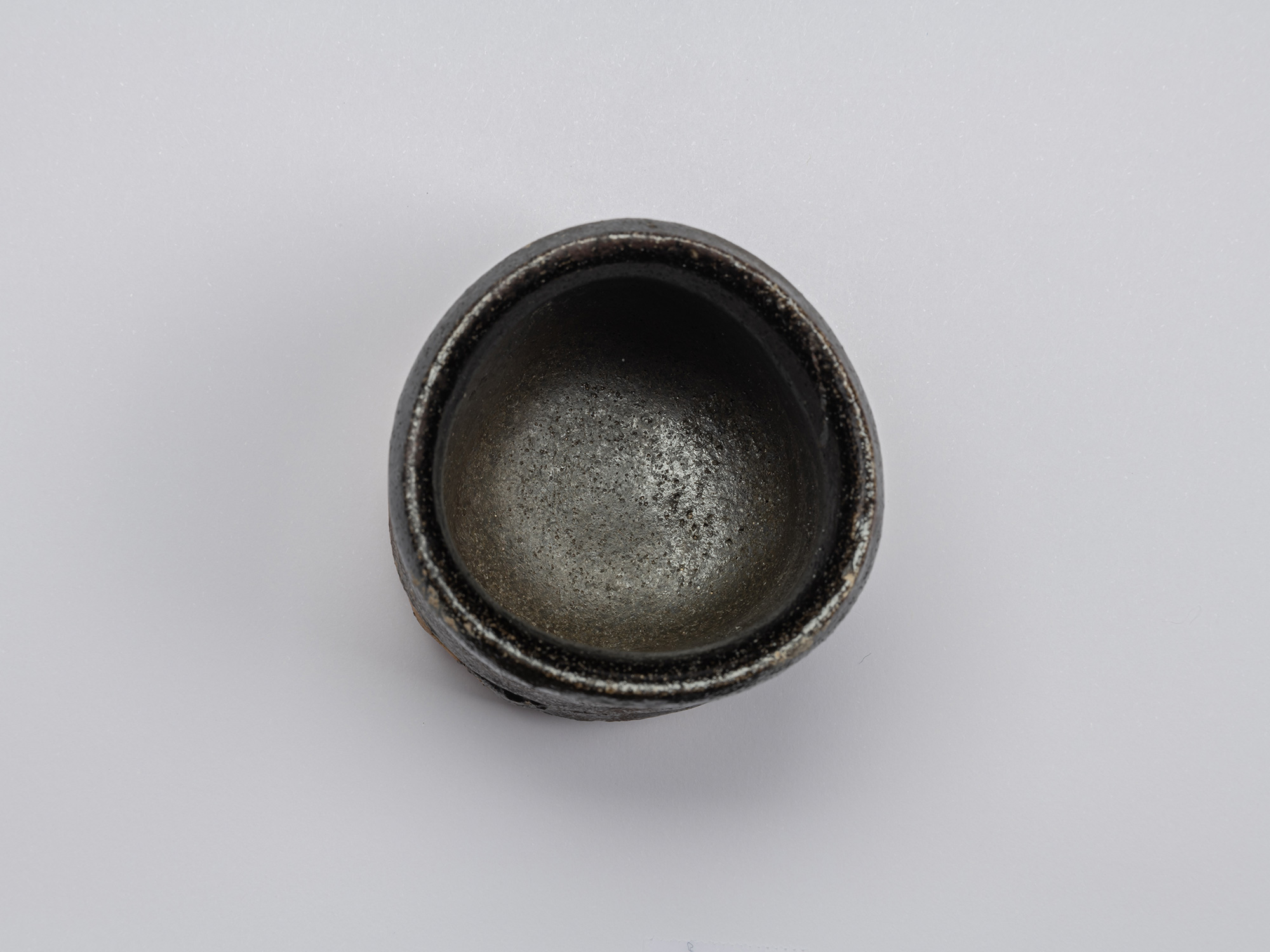 Overhead view into Shiro Tsujimura’s Kuro Guinomi, showing a dark, subtly lustrous interior with...