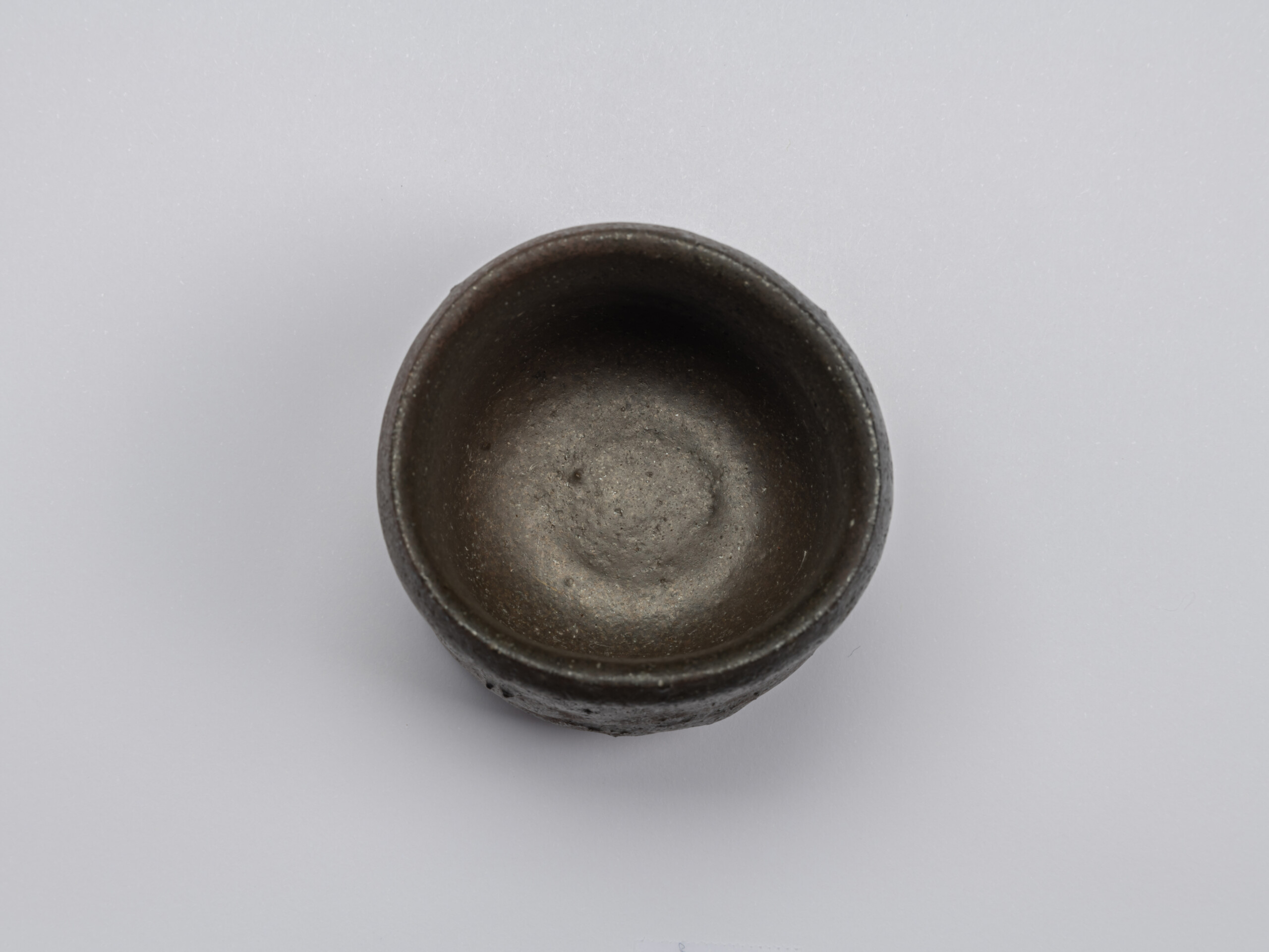 Overhead view into Shiro Tsujimura’s Kuro Guinomi, showing a dark brown-black interior with a subtly...