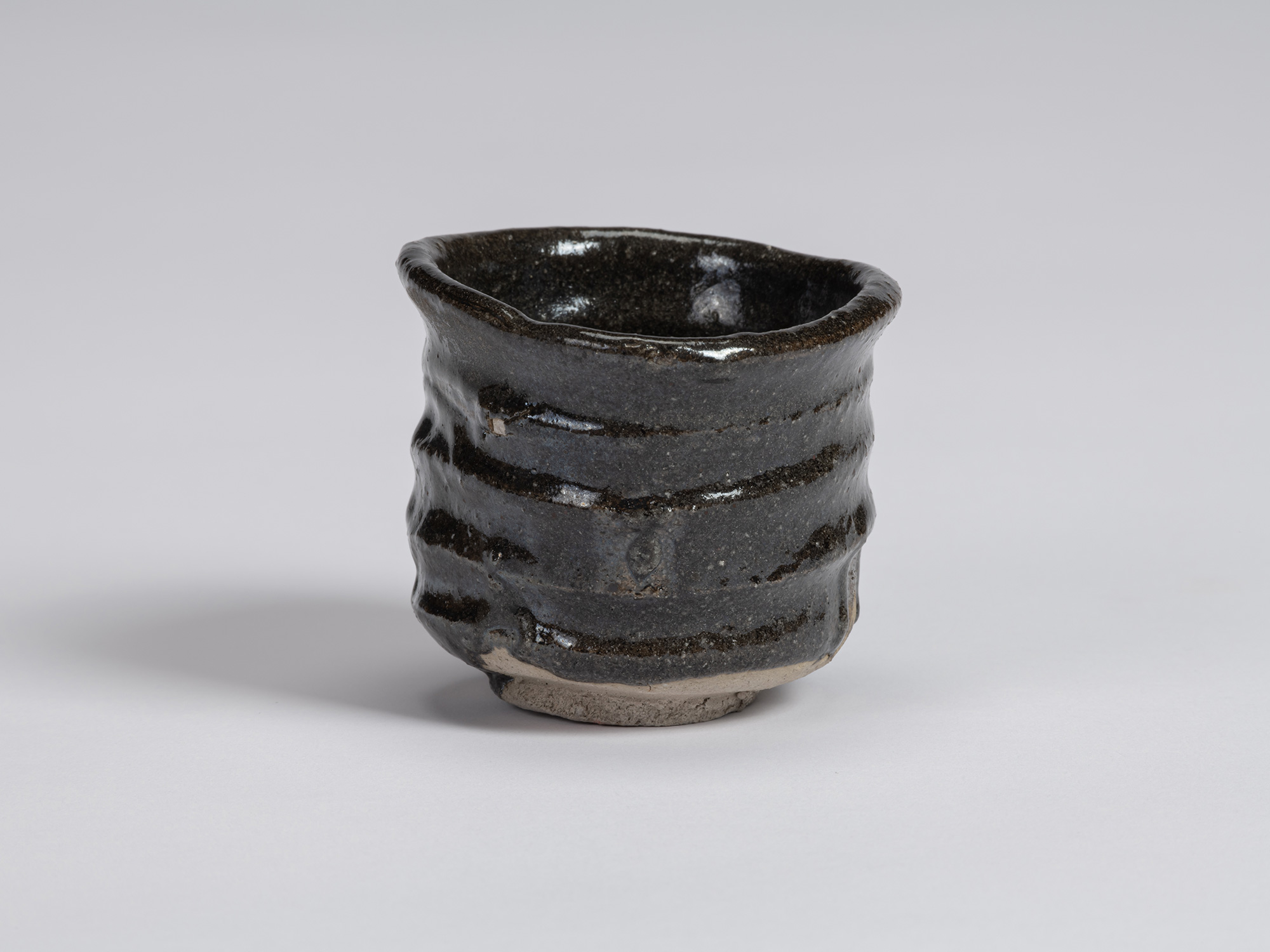 View of a Kuro Guinomi by Shiro Tsujimura, with an irregular cylindrical form, undulating rim,...