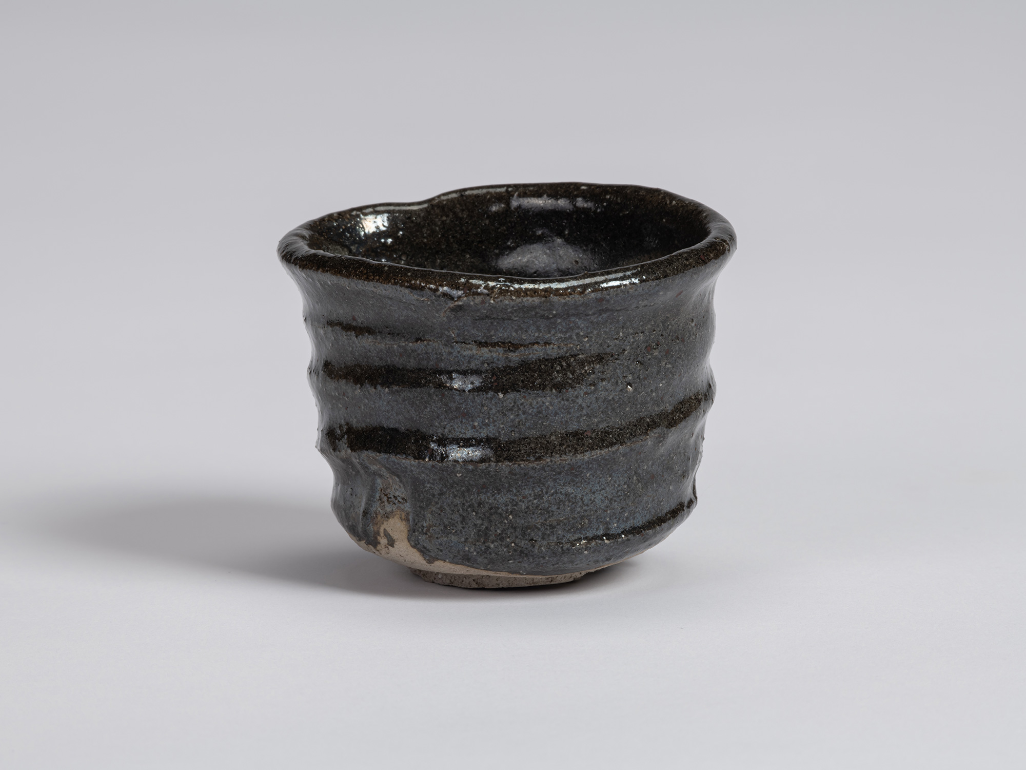 View of a Kuro Guinomi by Shiro Tsujimura, with an irregular cylindrical form, undulating rim,...