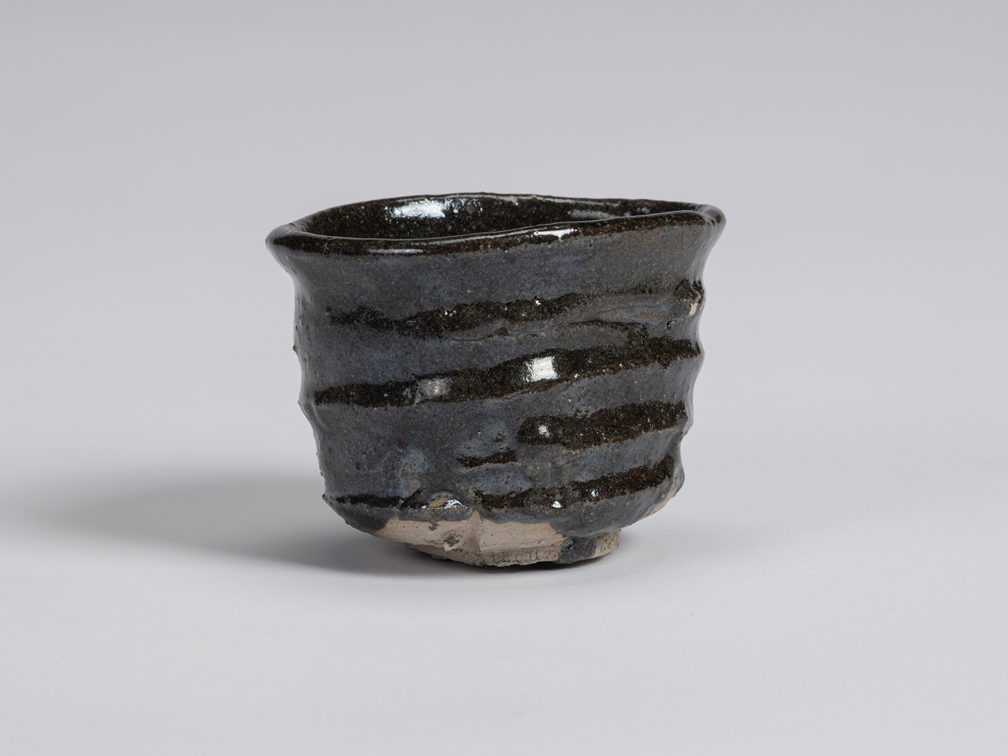 View of a Kuro Guinomi by Shiro Tsujimura, with an irregular cylindrical form, undulating rim,...