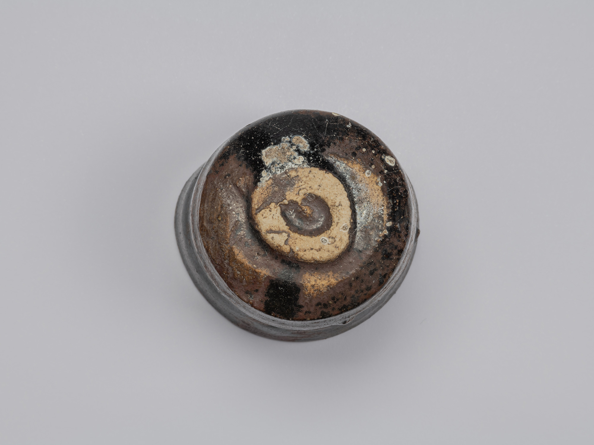 Underside of Kuro Guinomi by Shiro Tsujimura, showing the small circular foot surrounded by exposed...