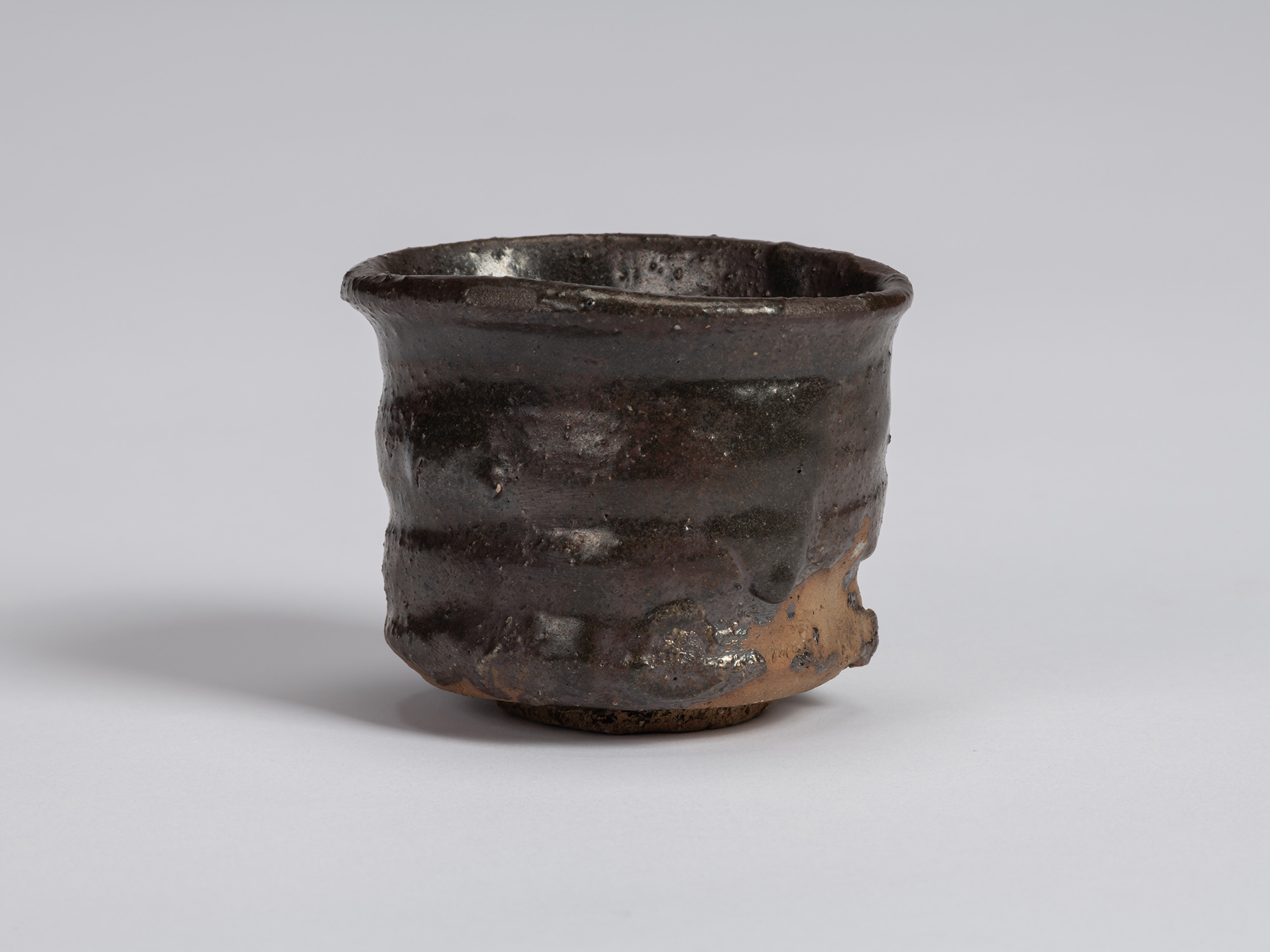 Kuro guinomi by Shiro Tsujimura with an irregular cylindrical form, subtly flared rim, horizontal...