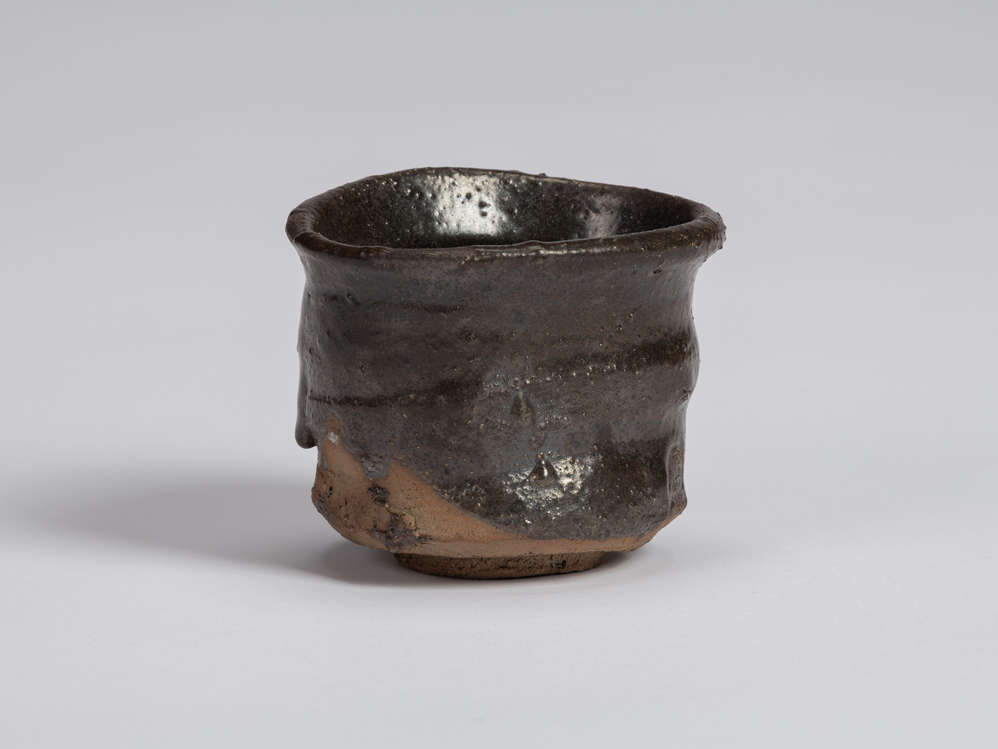 Kuro guinomi by Shiro Tsujimura with an irregular cylindrical form, subtly flared rim, horizontal...