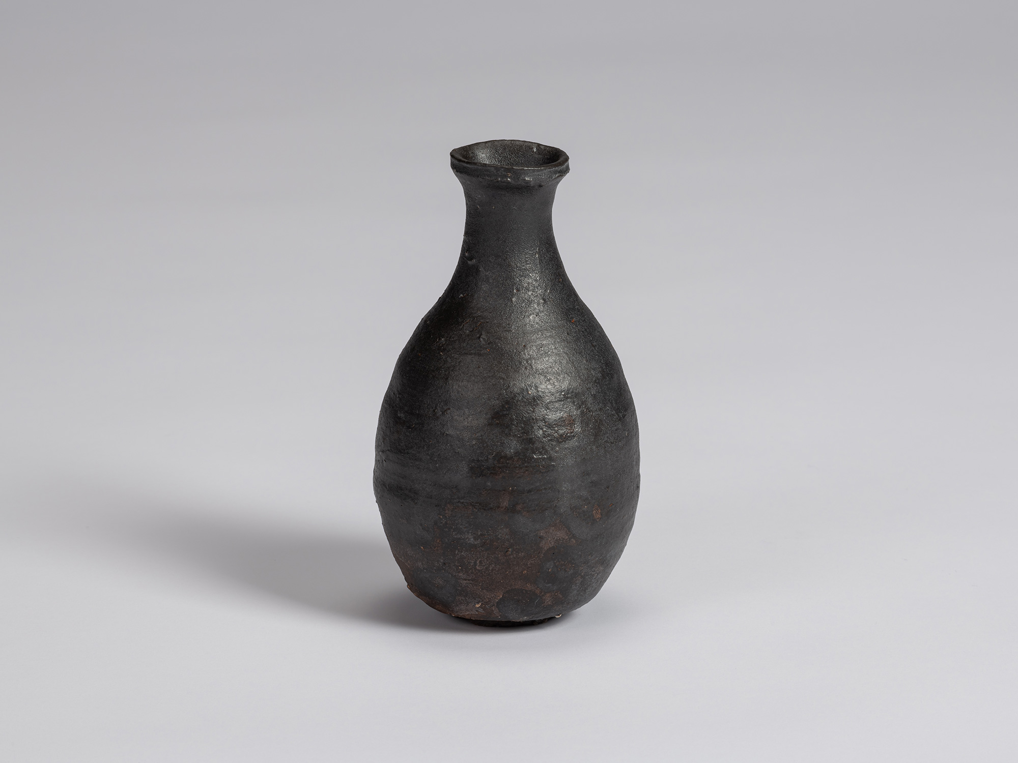 Kuro Tokkuri by Shiro Tsujimura, with a full, pear-shaped body, narrow neck, and irregular flared...