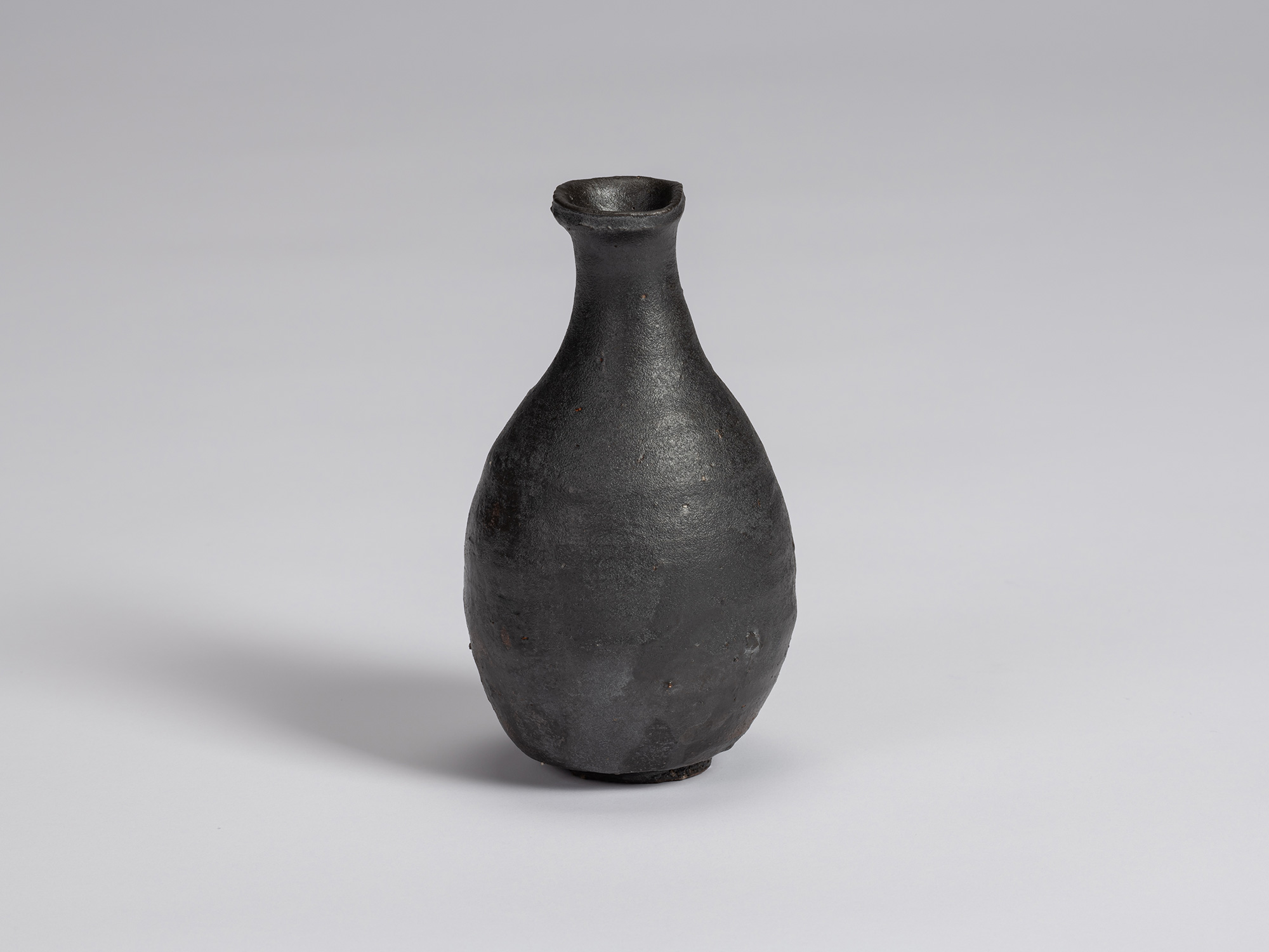 Kuro Tokkuri by Shiro Tsujimura, with a full, pear-shaped body, narrow neck, and irregular flared...