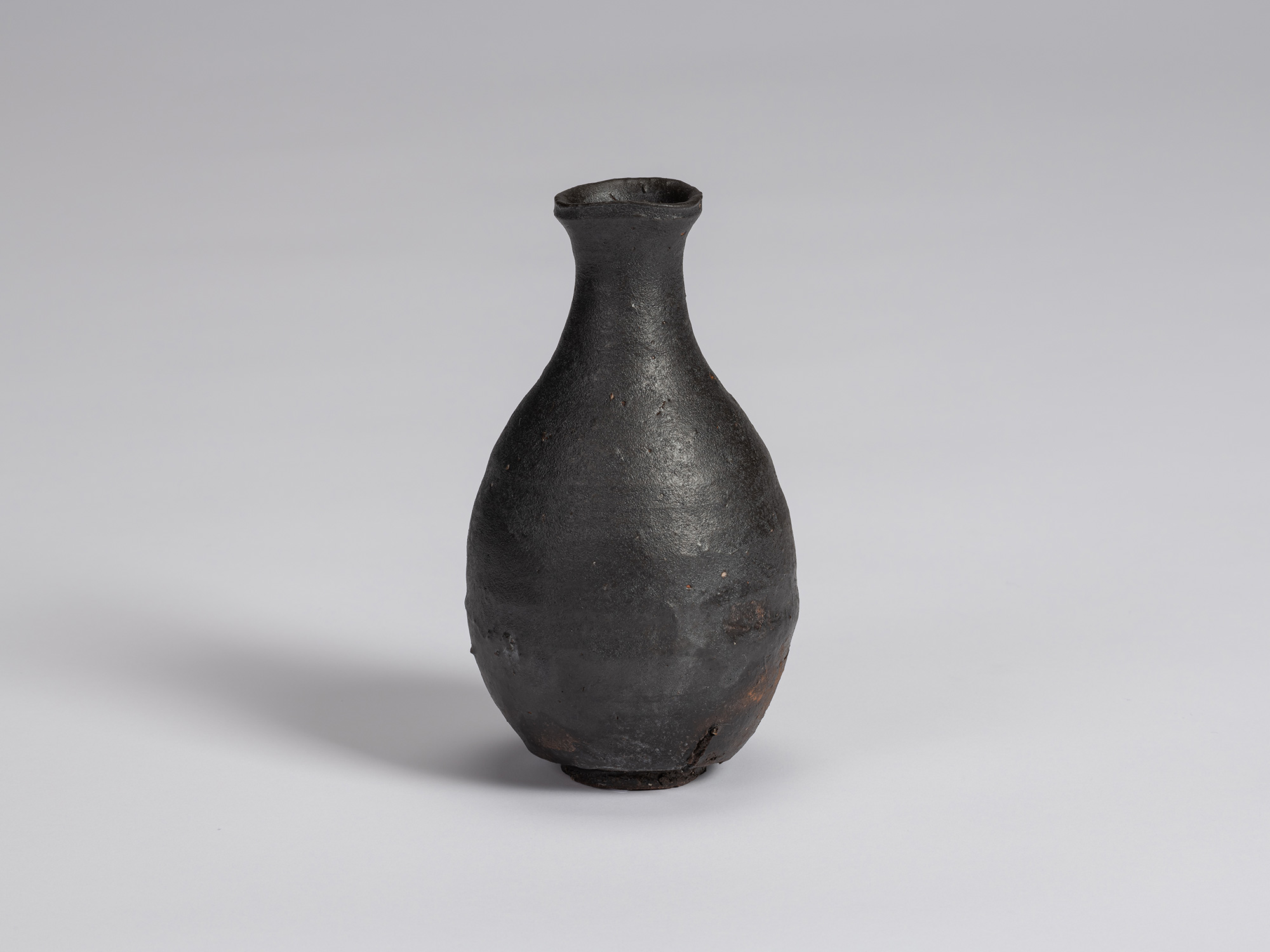 Kuro Tokkuri by Shiro Tsujimura, with a full, pear-shaped body, narrow neck, and irregular flared...