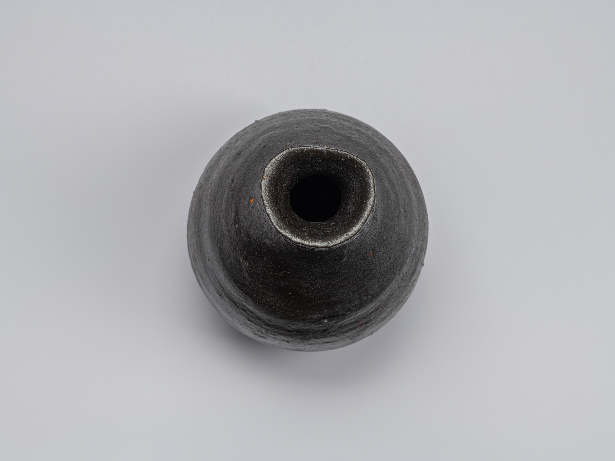 Overhead view of the Kuro Tokkuri by Shiro Tsujimura, showing its irregular rounded mouth, thick...