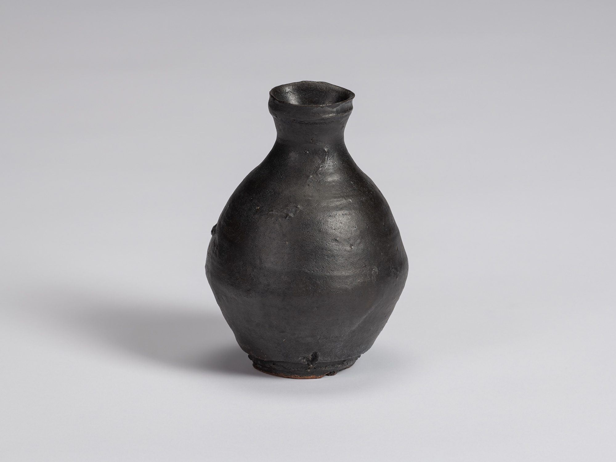 Kuro Tokkuri by Shiro Tsujimura, with a plump, rounded body, short narrow neck, and irregular flared...
