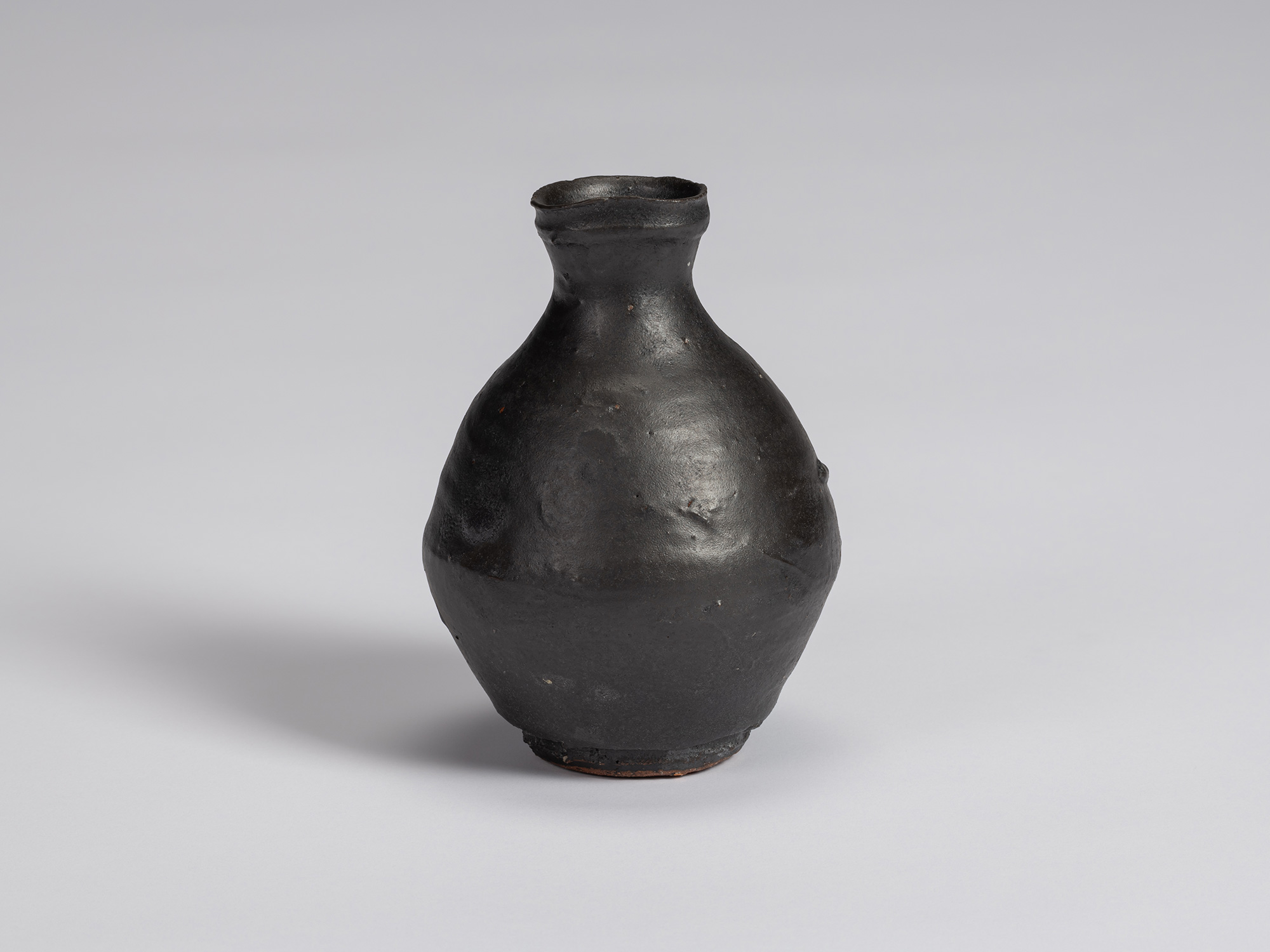 Kuro Tokkuri by Shiro Tsujimura, with a plump, rounded body, short narrow neck, and irregular flared...
