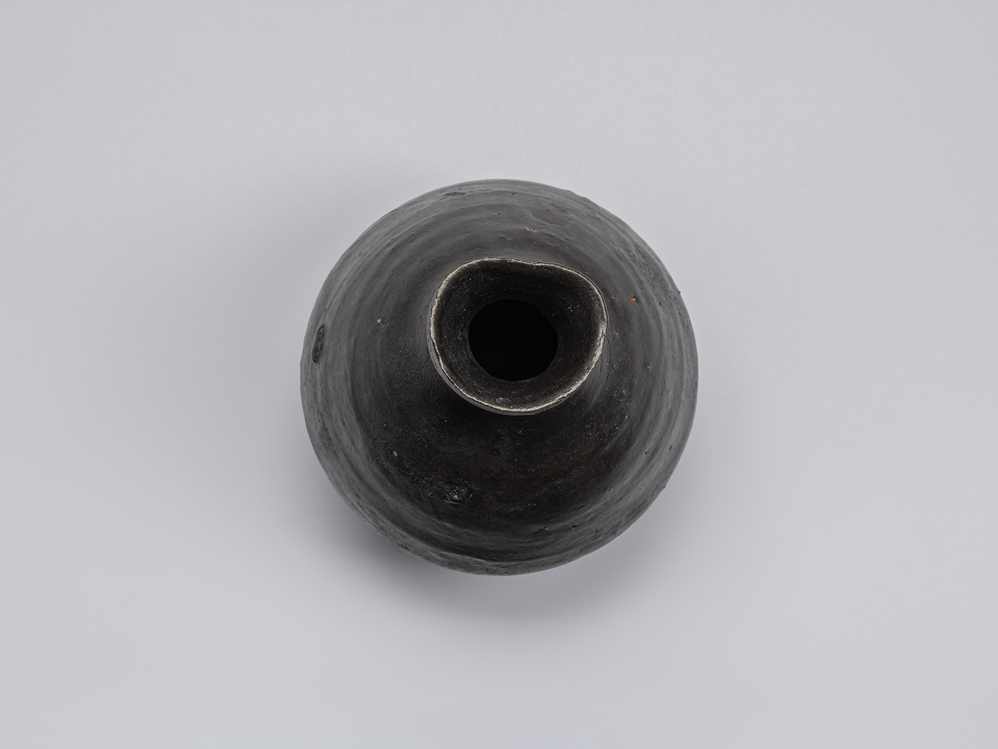 Overhead view of the Kuro Tokkuri by Shiro Tsujimura, showing the irregular rounded mouth, thick...