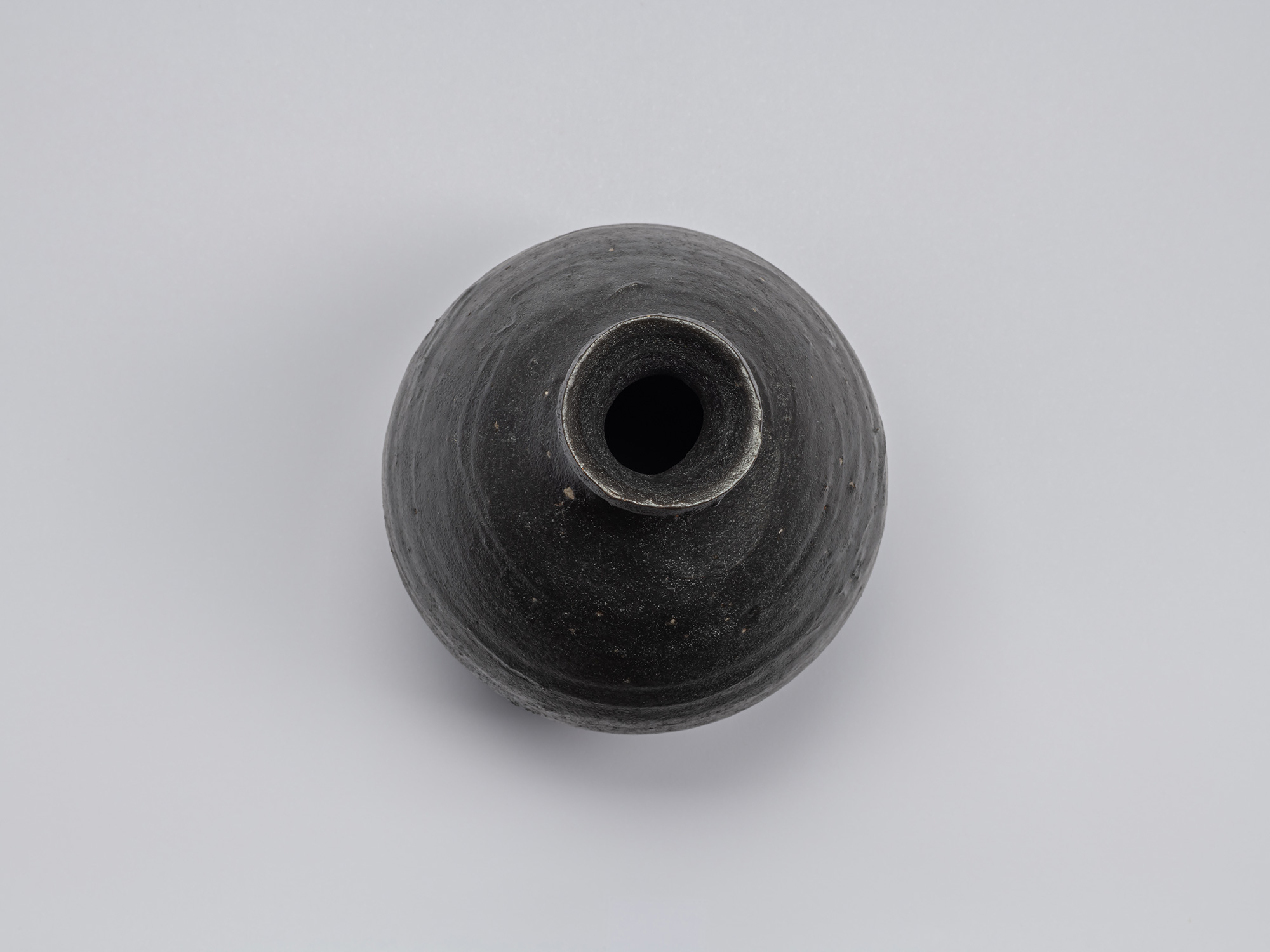 Overhead view of the Kuro Tokkuri by Shiro Tsujimura, showing the rounded mouth, thick irregular...