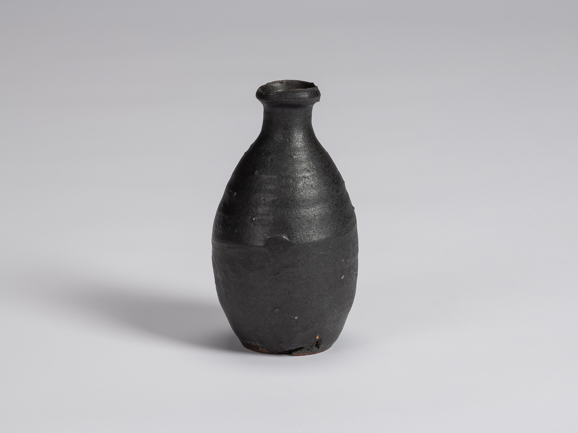 Kuro Tokkuri by Shiro Tsujimura, with an elongated oval body, narrow neck, and irregular flared...